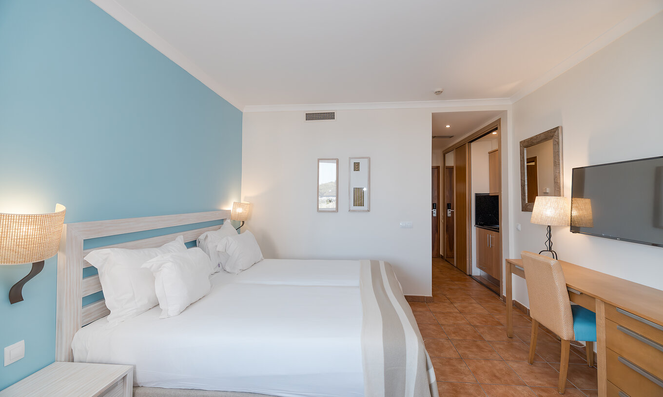 The Deluxe Garden View at Pestana Viking has two beds, bedside table, desk and TV