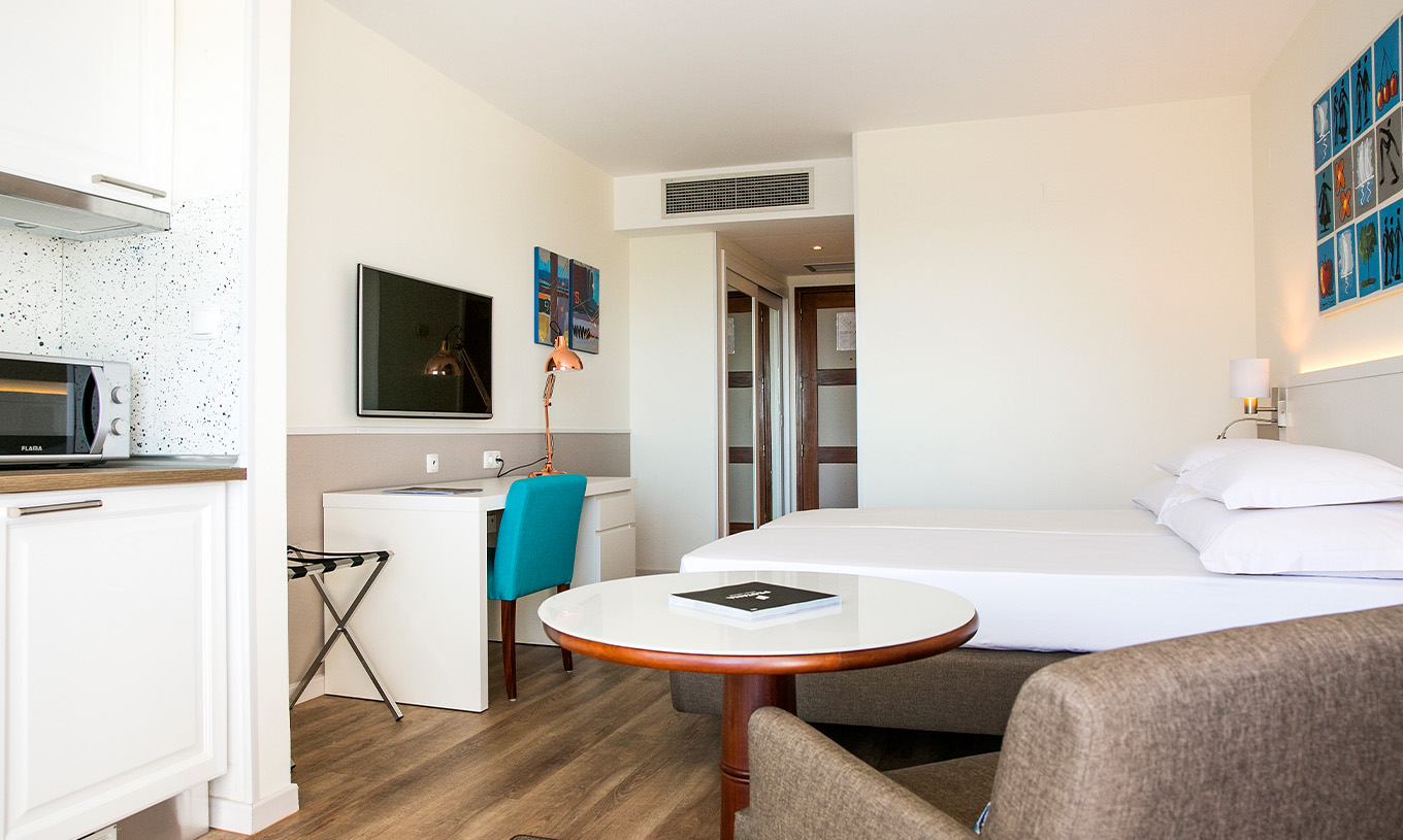 The Deluxe Sea View room at Pestana Cascais has two single beds, a TV, a desk, and a kitchenette
