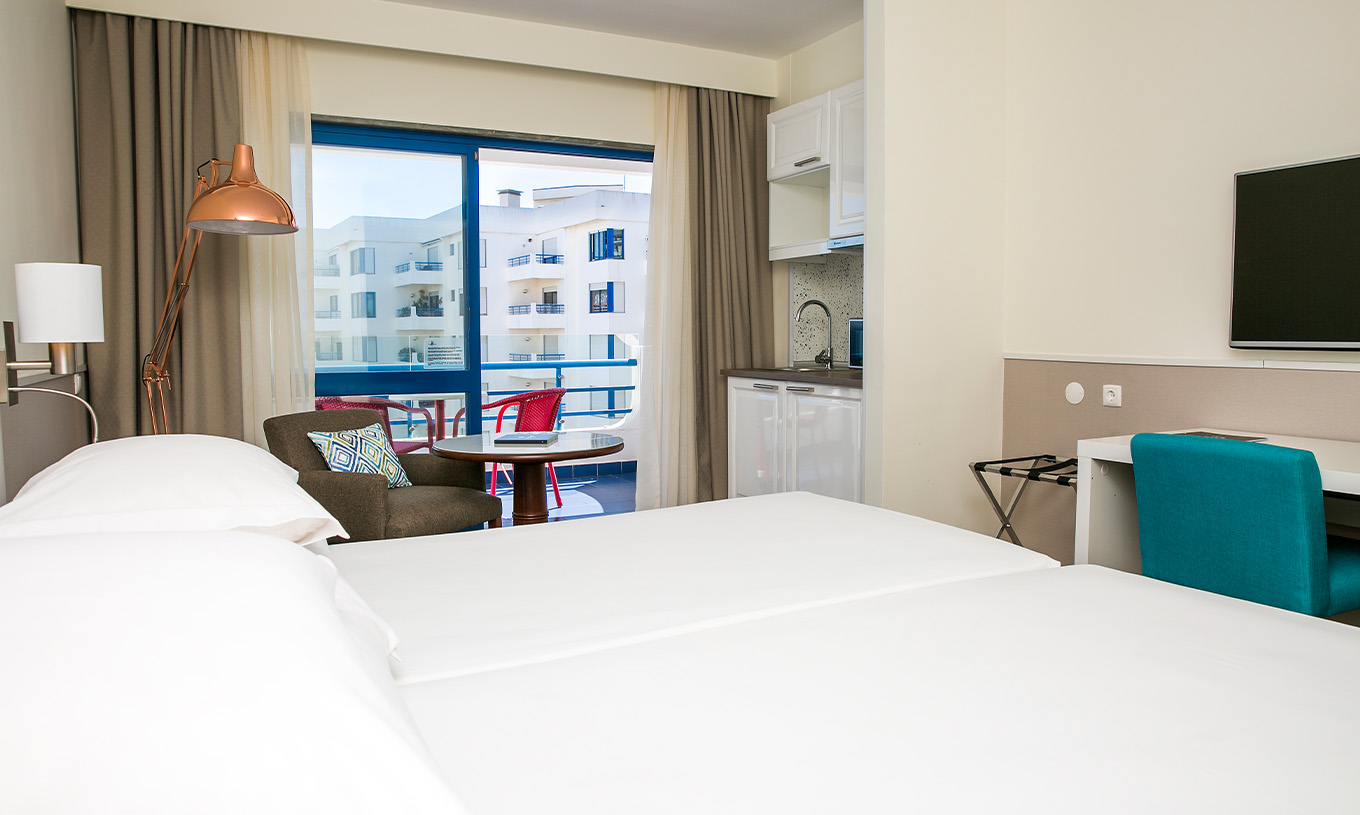 The Superior Deluxe room at Pestana Cascais has two single beds, a TV, and a balcony with chairs and tables