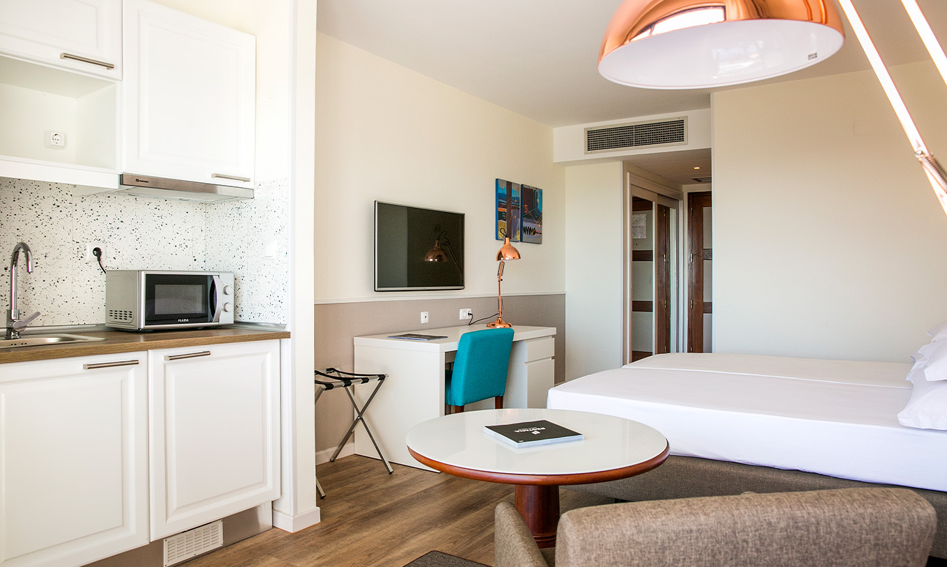The Deluxe room at Pestana Cascais has two single beds, a TV, a desk, and a kitchenette