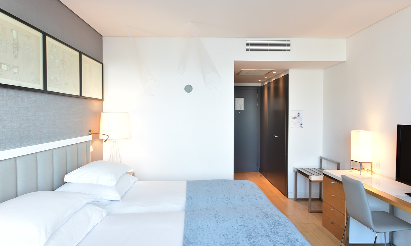 The Double Room Art District at Pestana Cidadela Cascais has a small hallway at the entrance, two beds, and an art wall