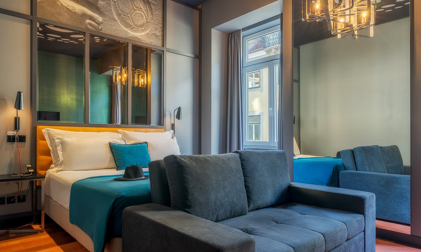 The CR7 Familiar Hat-Trick has a sofa a bed and a mirror above the bed at Pestana CR7 Lisboa