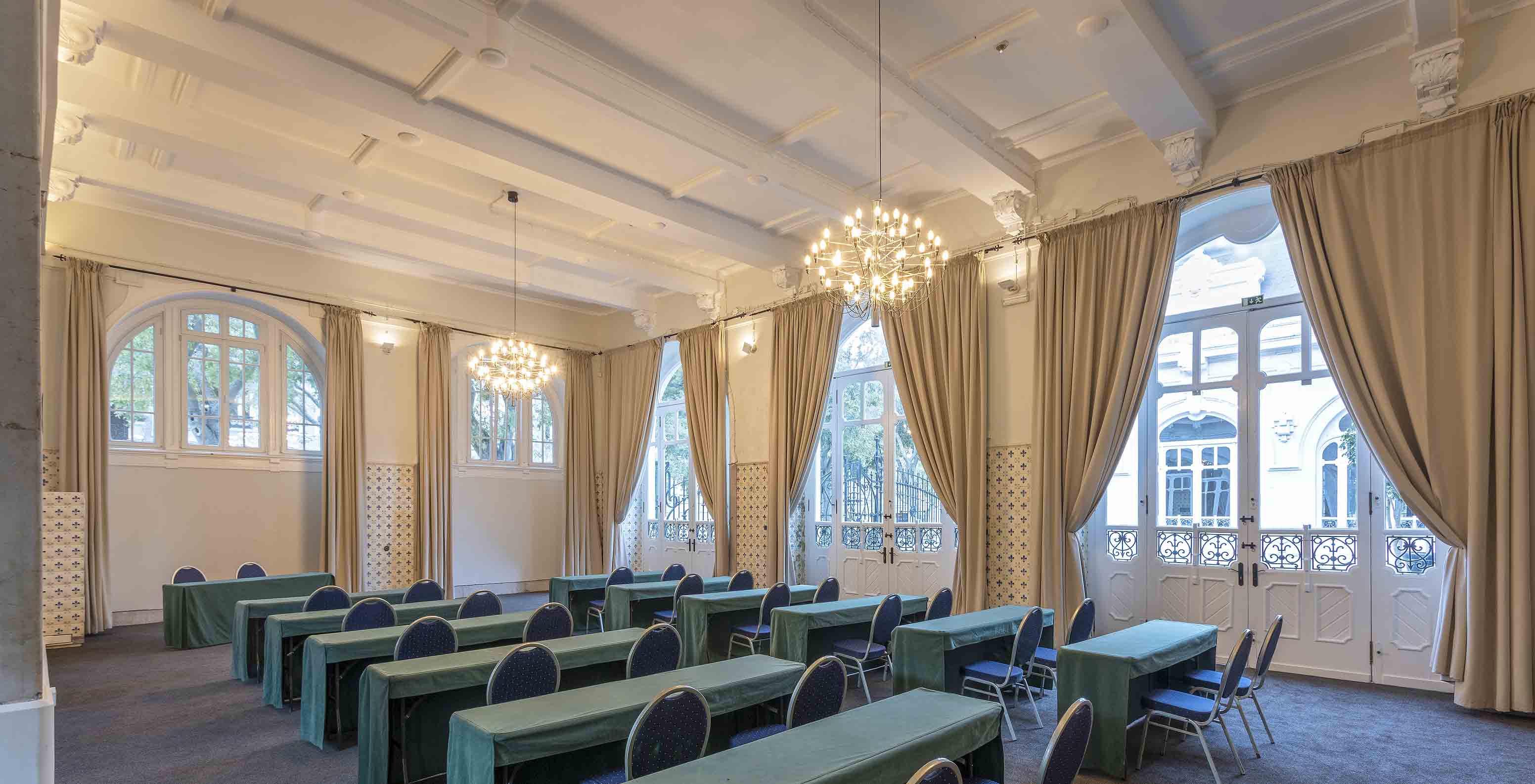 Pestana Palace Lisboa has a meeting room with long green tables, blue chairs, and several windows