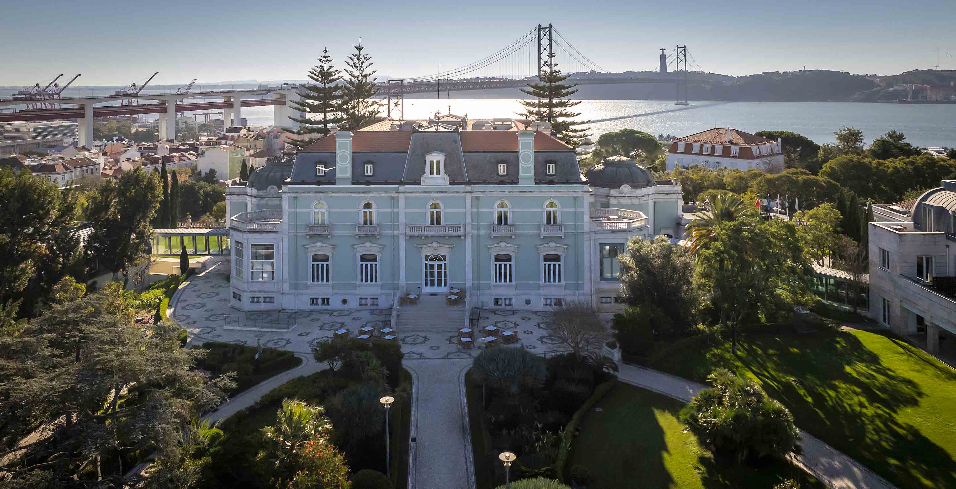 Aerial view of the main building of Pestana Palace with the 25 de Abril Bridge and the Tagus River in the background