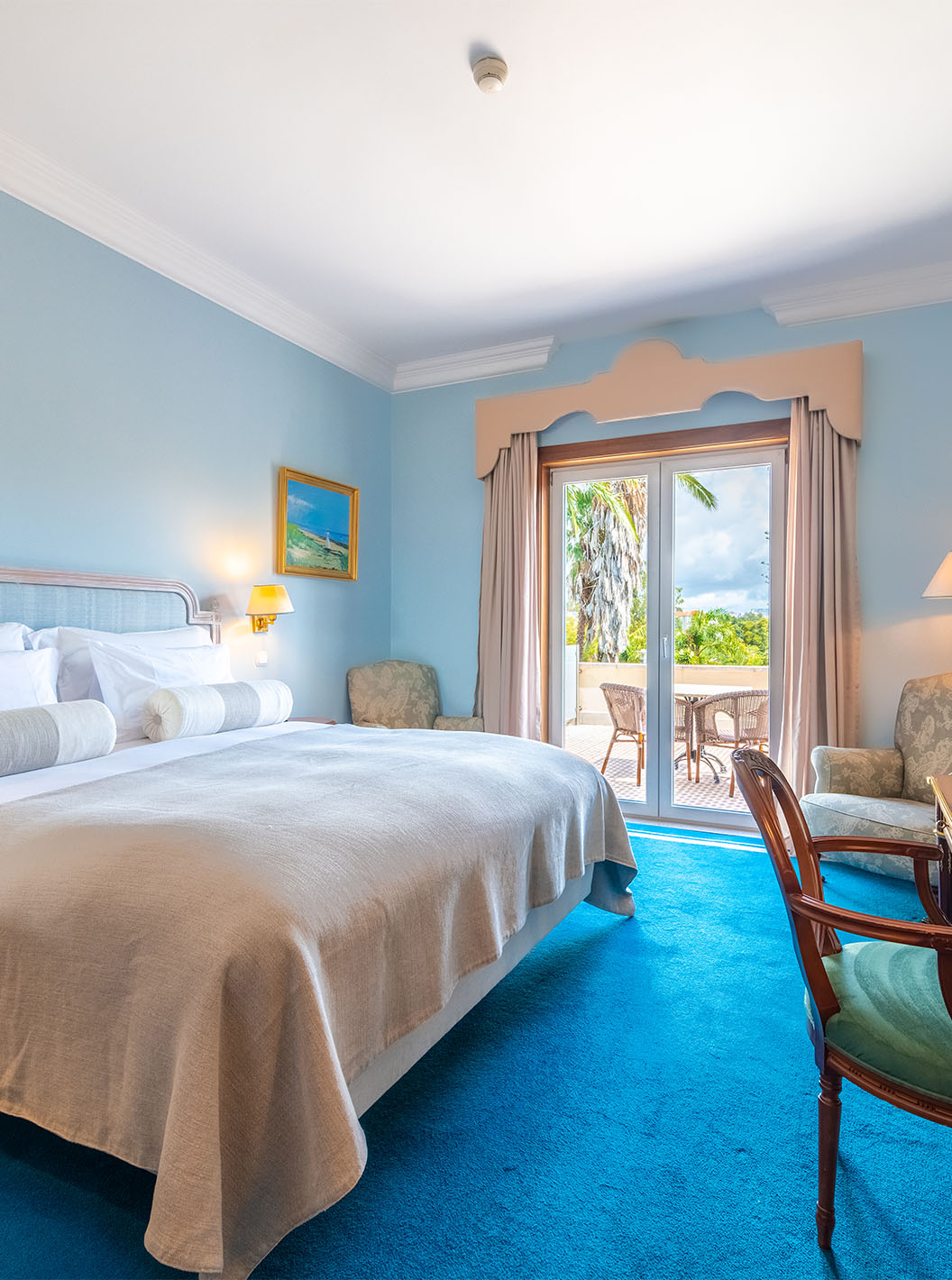 The Premium Balcony room at Pestana Palace Lisbon includes a double bed, light blue painted walls, and a window with curtains