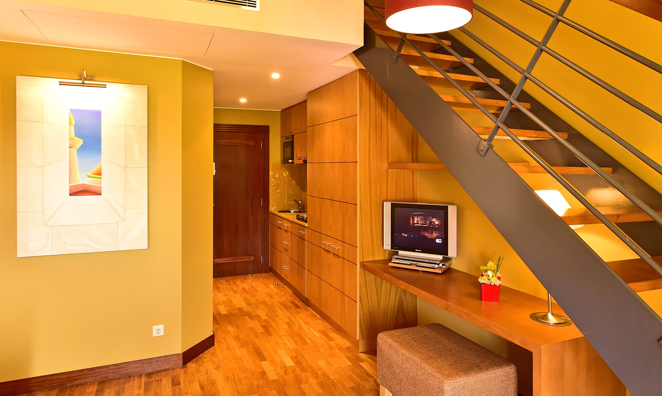 The Mezzanine Jacuzzi Suite of Pestana Sintra Golf has a table with television, a picture on the wall, and a kitchenette