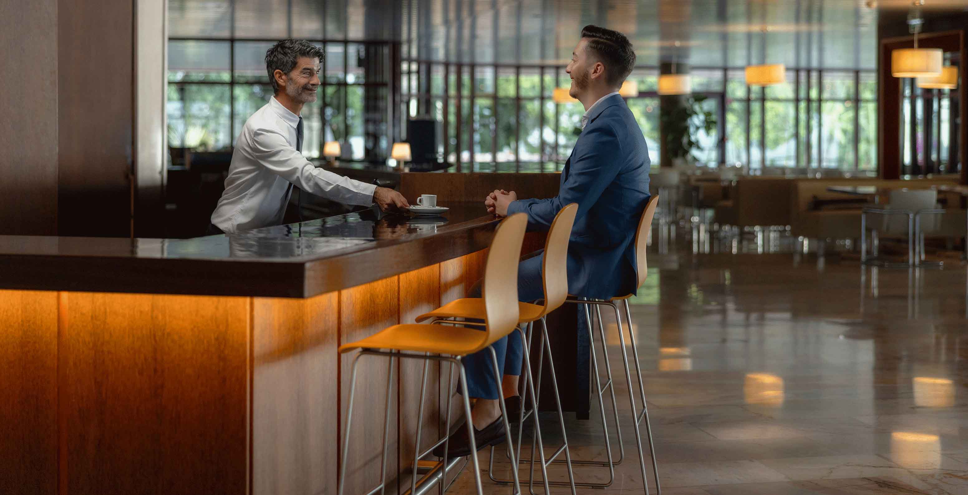 The bar area of the hotel in Funchal on the seafront, with a spa and swimming pool, with a gentleman serving drinks at the counter.