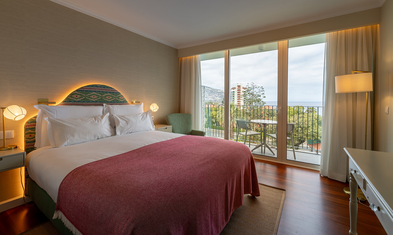 The Partial Sea View Room at Pestana Quinta Perestrello has a double bed, a balcony with a table, chairs, and a sea view.