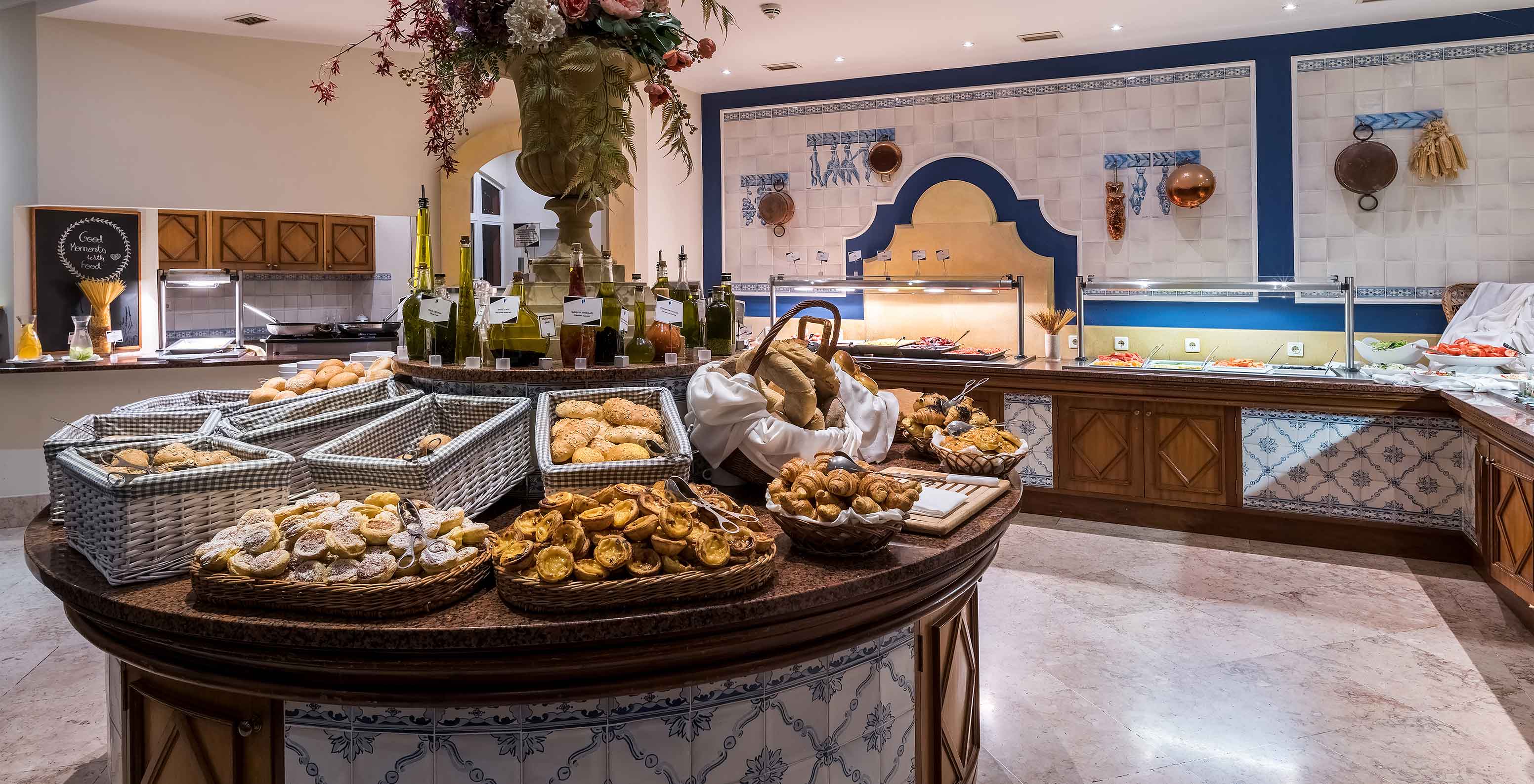 Breakfast room with various breads and pastries in baskets on a round table at Pestana Village, Hotel with Pool in Funchal