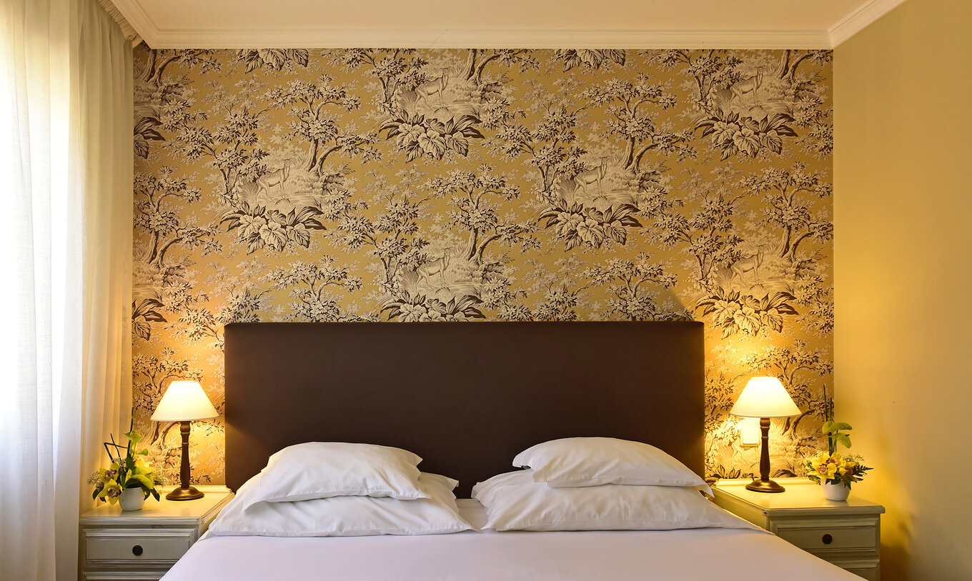 The Superior Twin with Jacuzzi at Pestana Village has a double bed with headboard and brown bedspread, and wallpaper