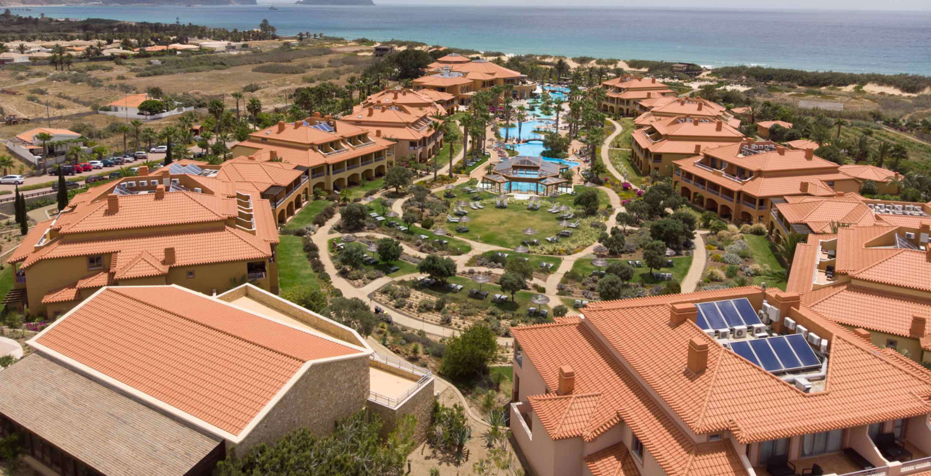 Drone view of Pestana Porto Santo All Inclusive, with several villas around the pool and greenery