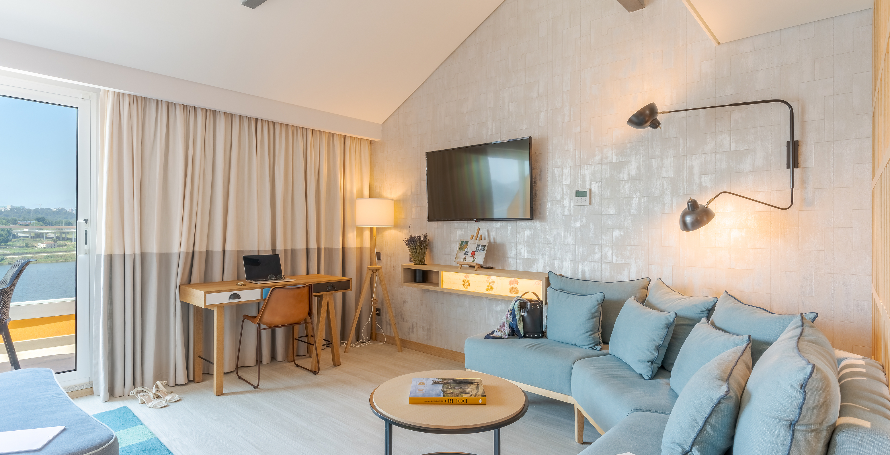 The Junior Suite at Pestana Douro Riverside features a television, a desk with a table, and a sofa