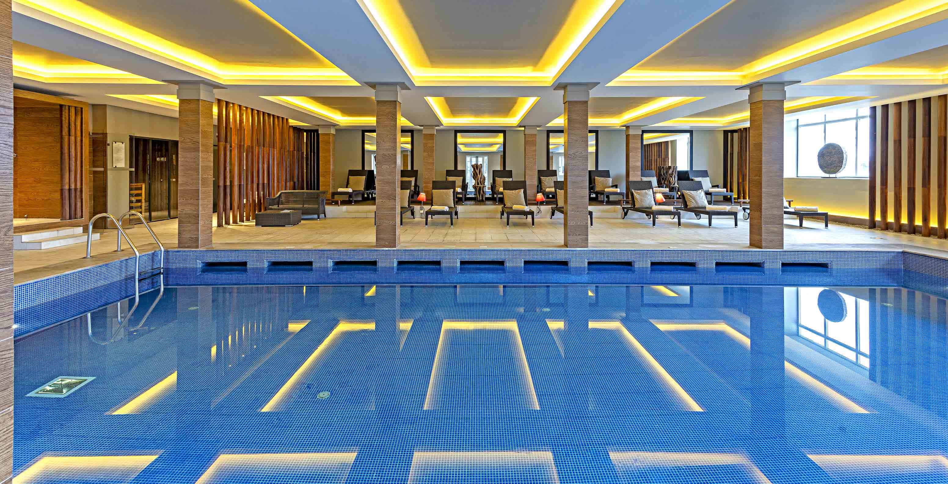 Indoor pool of Pestana Palácio do Freixo, a hotel on the Douro River with spa and pool, with loungers and cushions