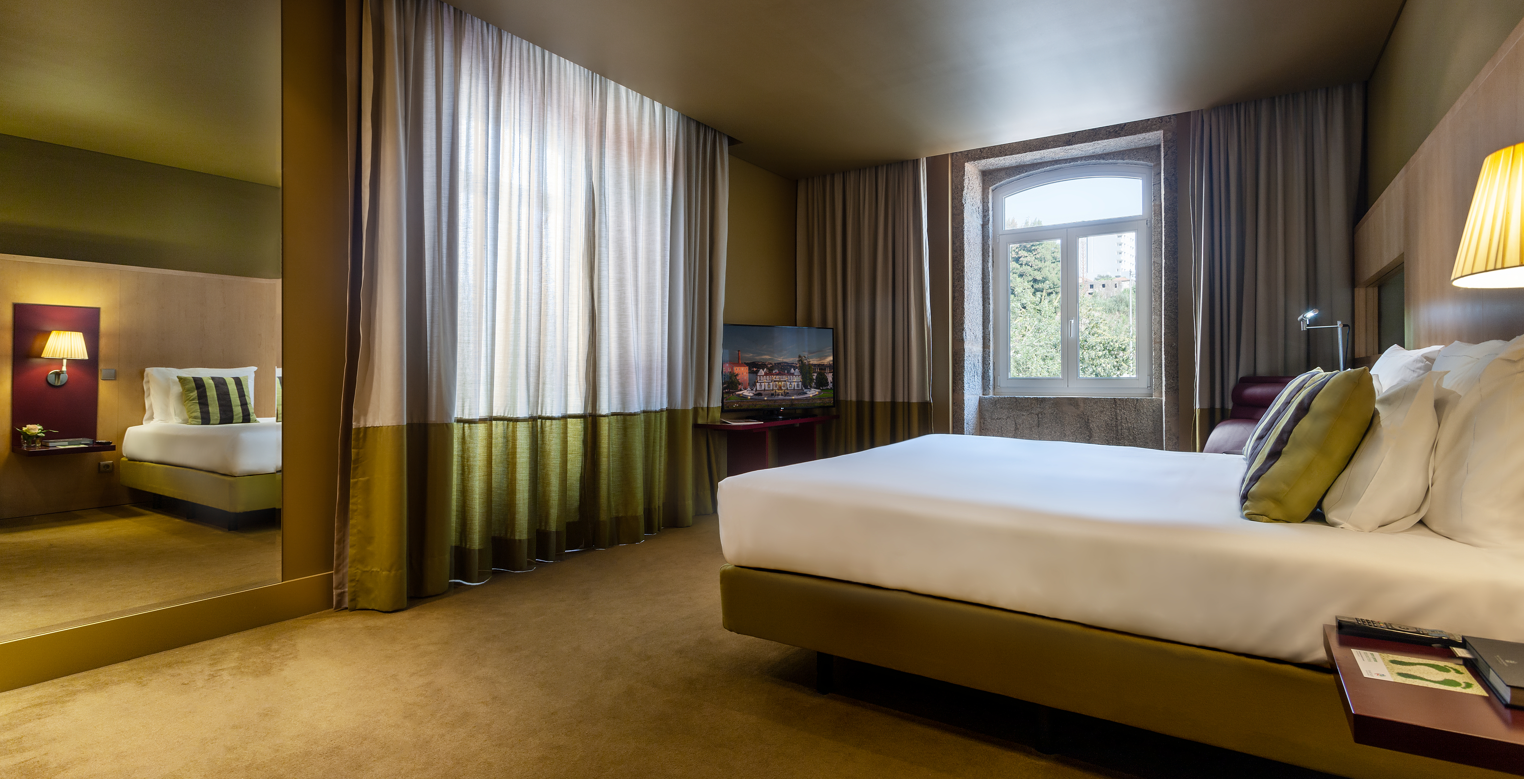 The Junior Suite of Pestana Palácio do Freixo has a double bed, a mirror and two windows with curtains