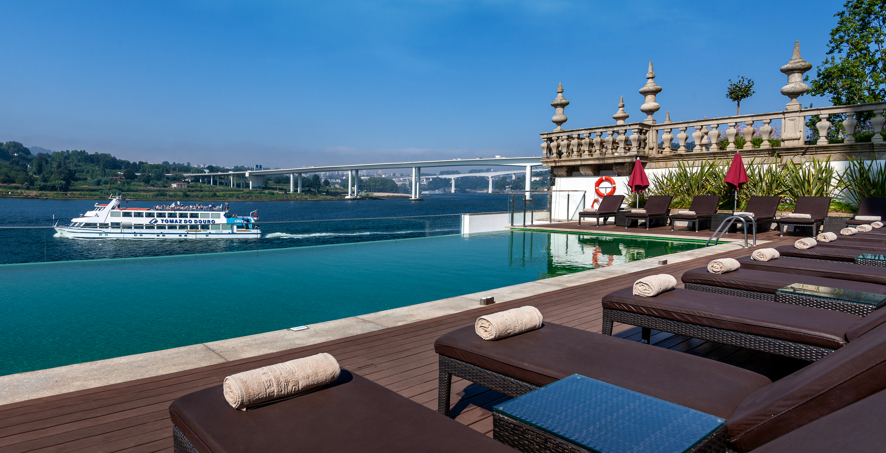 Outdoor pool of Pestana Palácio do Freixo, a hotel on the Douro River with spa and pool, an infinity pool and the Douro River