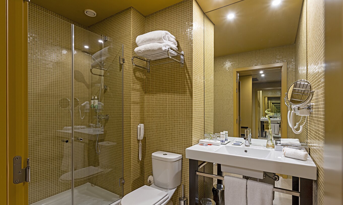 Pestana Palácio do Freixo’s Classic Attic has a bathroom with yellow tiles, toilet, and washbasin