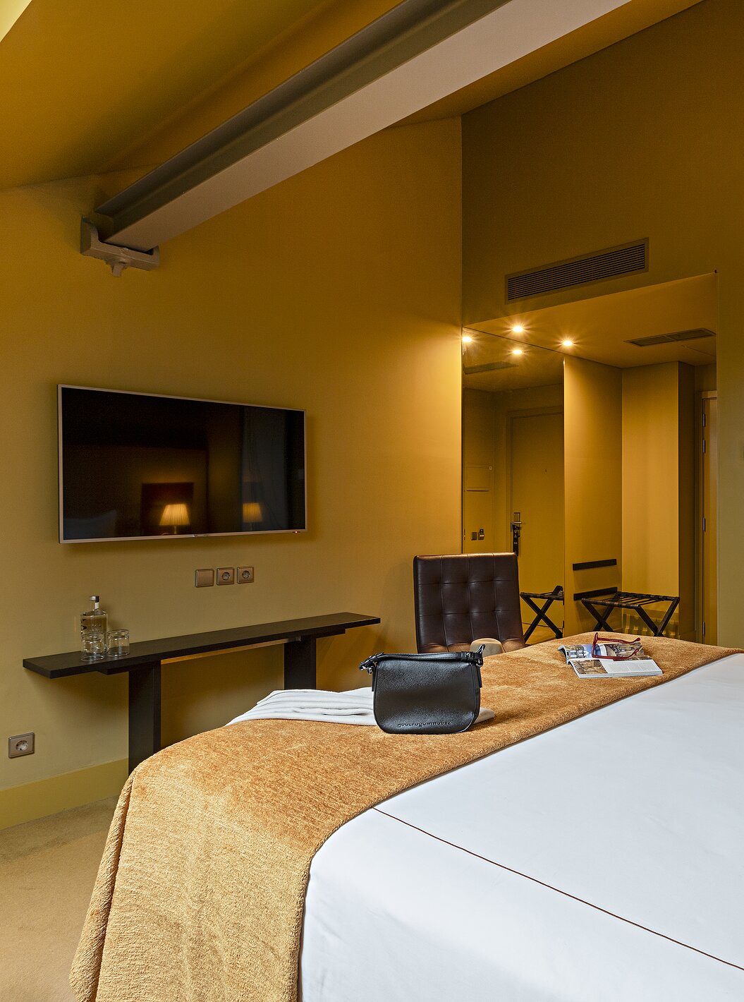 Pestana Palácio do Freixo’s Classic Attic has a double bed, TV in front, and a table with water