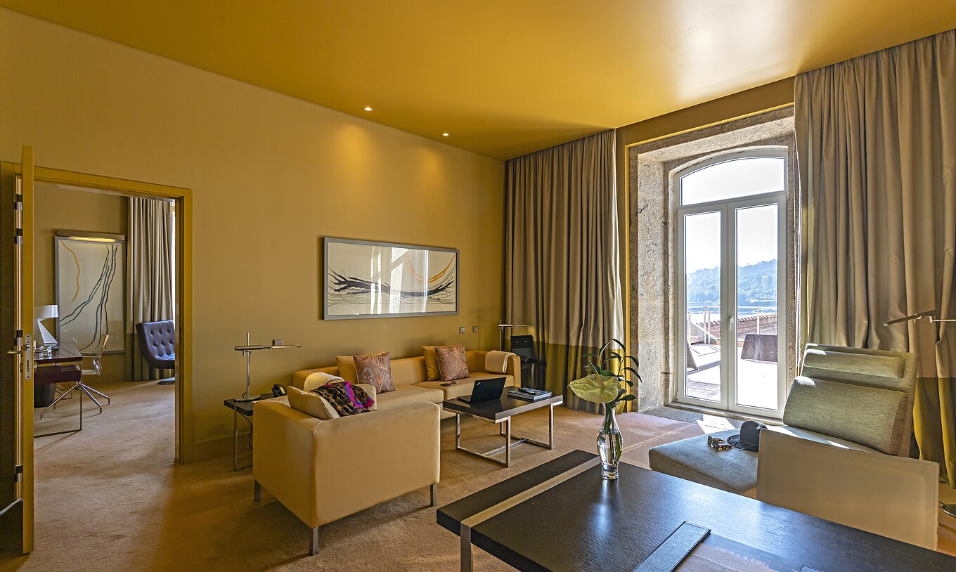 The Suite Nasoni has a living room with sofas, a desk, and a stone-framed window to the balcony