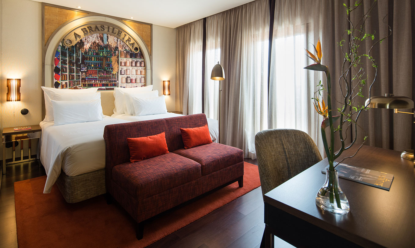 Premium Origin French Balcony Room at Pestana Porto - A Brasileira with desk, red sofa and large curtained windows