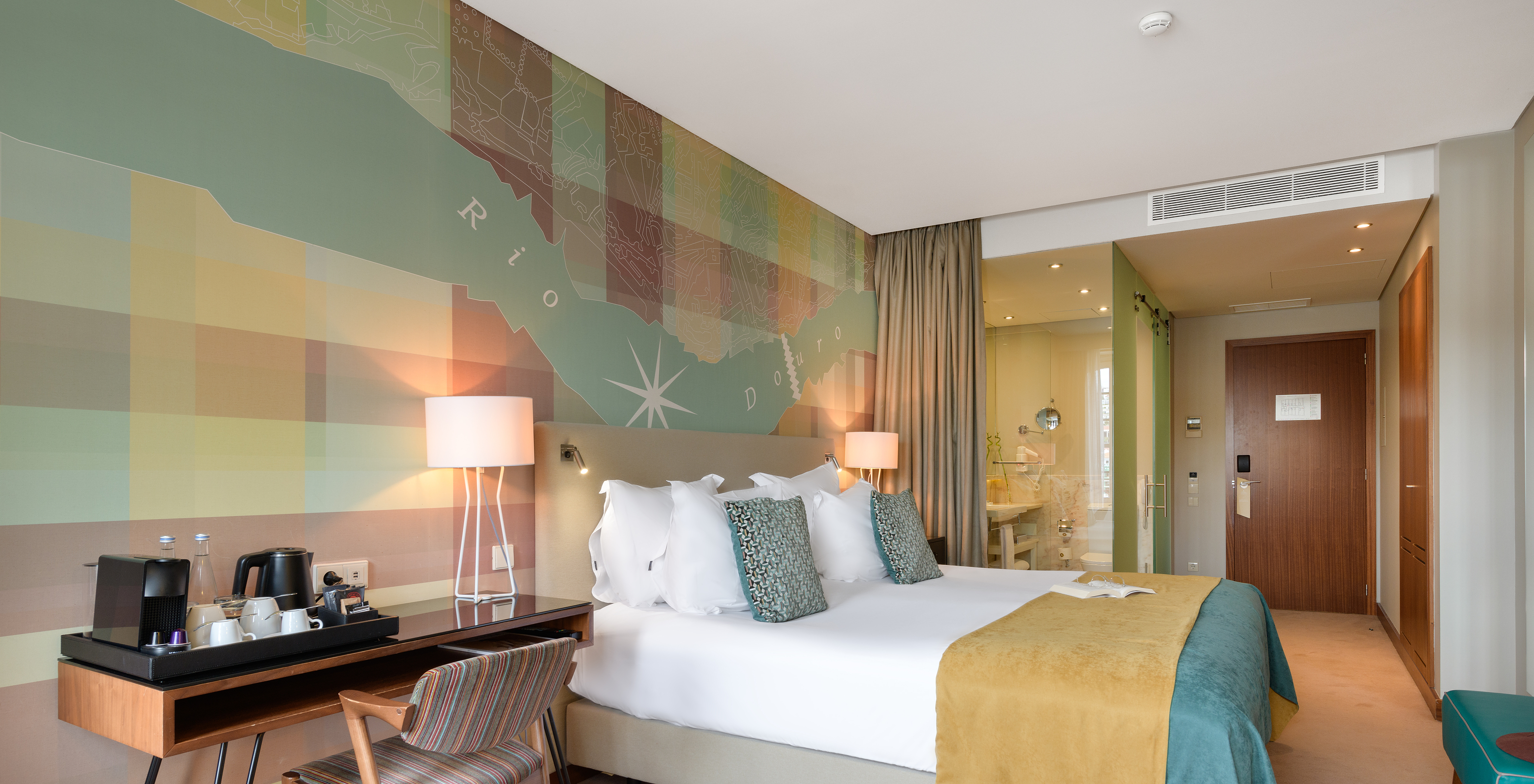 The Vintage River View room at Pestana Vintage Porto has a double bed with a yellow and blue bedspread and colorful wallpaper