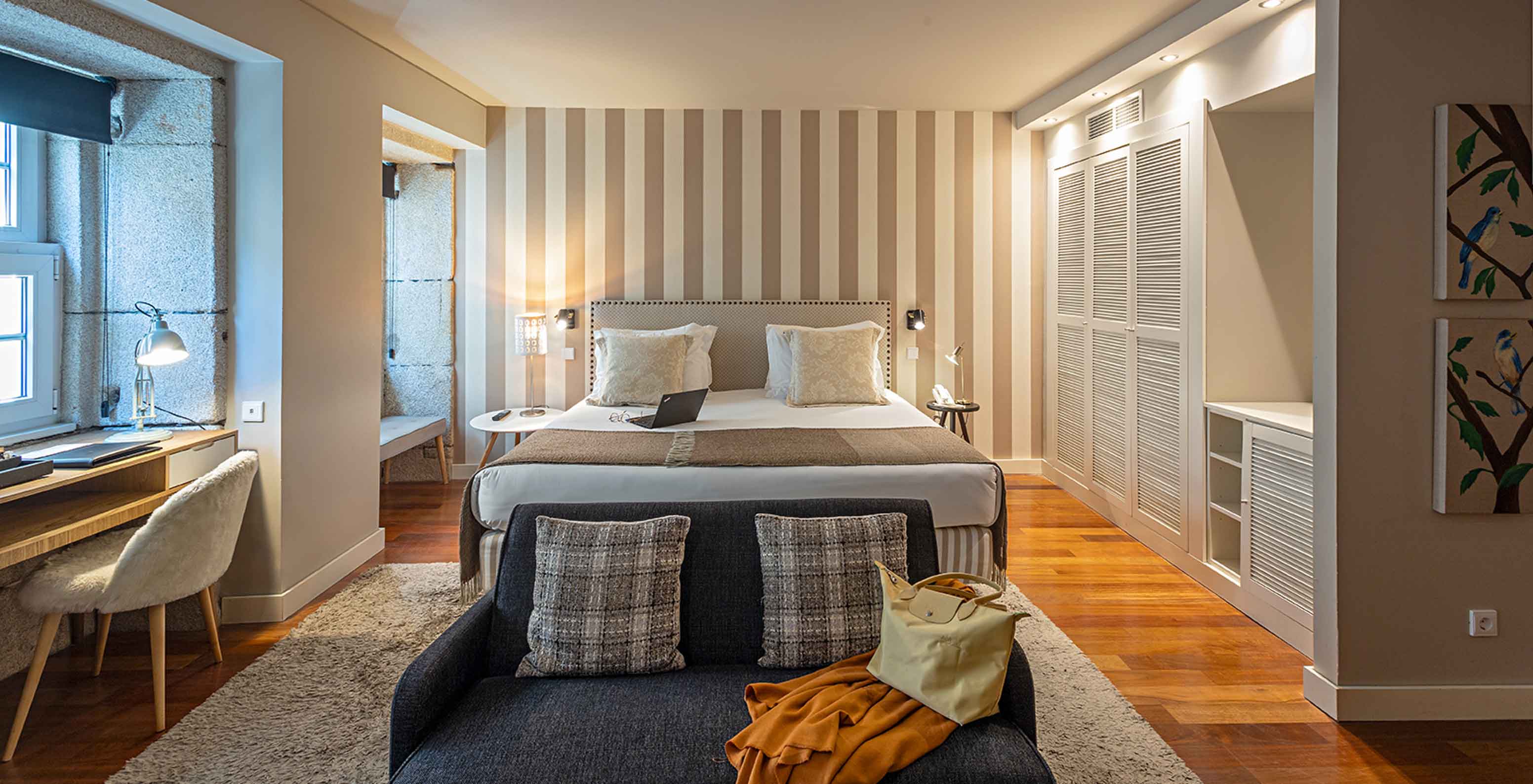 The Heritage Suite at Pestana Vintage Porto has a double bed, a sofa, two armchairs and striped wallpaper