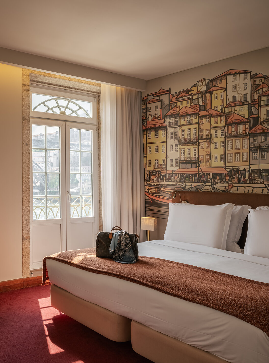 Plaza room at Pestana Vintage Porto featuring a bed, desk and balcony doors beside a Porto mural wall