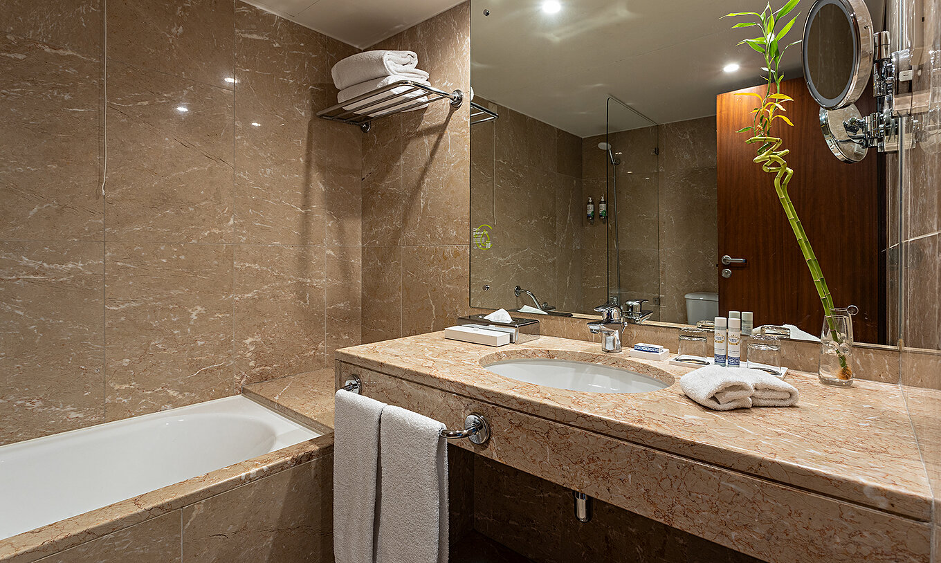 The Vintage River View at Pestana Vintage Porto has a brown marble bathroom with a sink and a bathtub