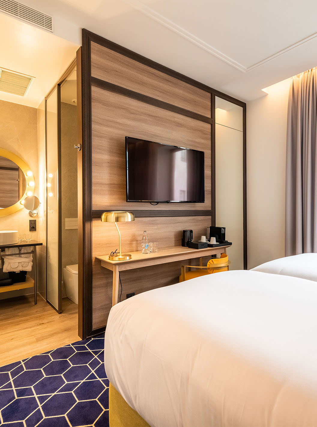 The Superior Room at Pestana CR7 Gran Vía Madrid includes two beds, a round mirror, and a window facing the courtyard