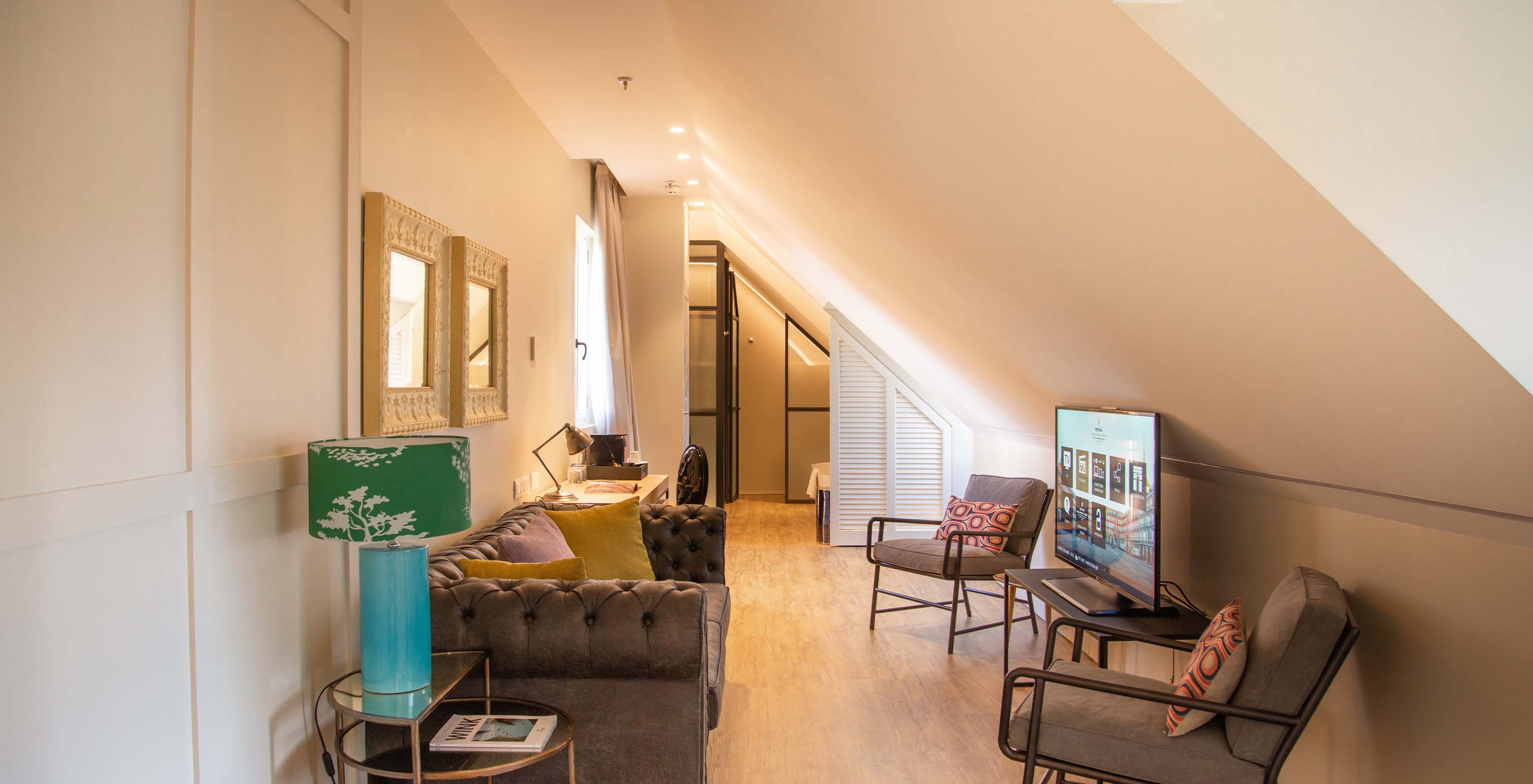 The Suite Plaza Mayor at Pestana Plaza Mayor Madrid has a living room with sofa, chairs, TV and paintings on the wall