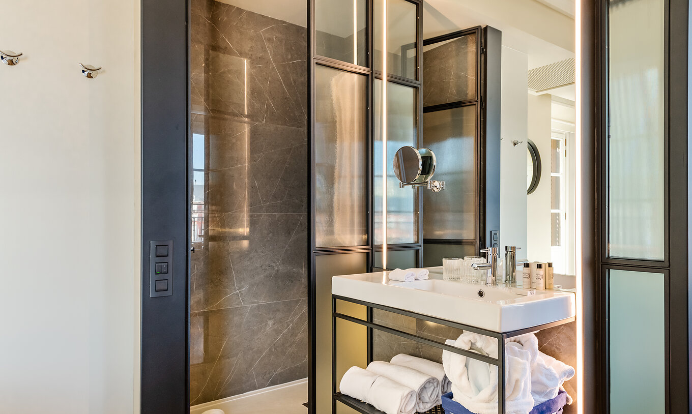 The Deluxe Plaza Mayor at Pestana Plaza Mayor Madrid has a bathroom with shower, sink, mirror, towels and amenities