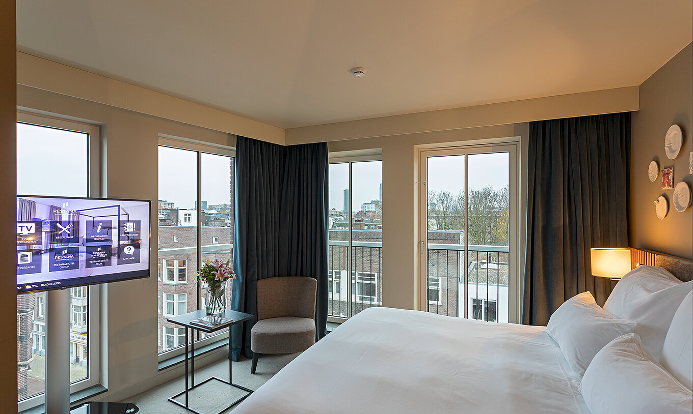 Classic Studio room at Pestana Amsterdam Riverside has a double bed, a lamp and windows overlooking the street