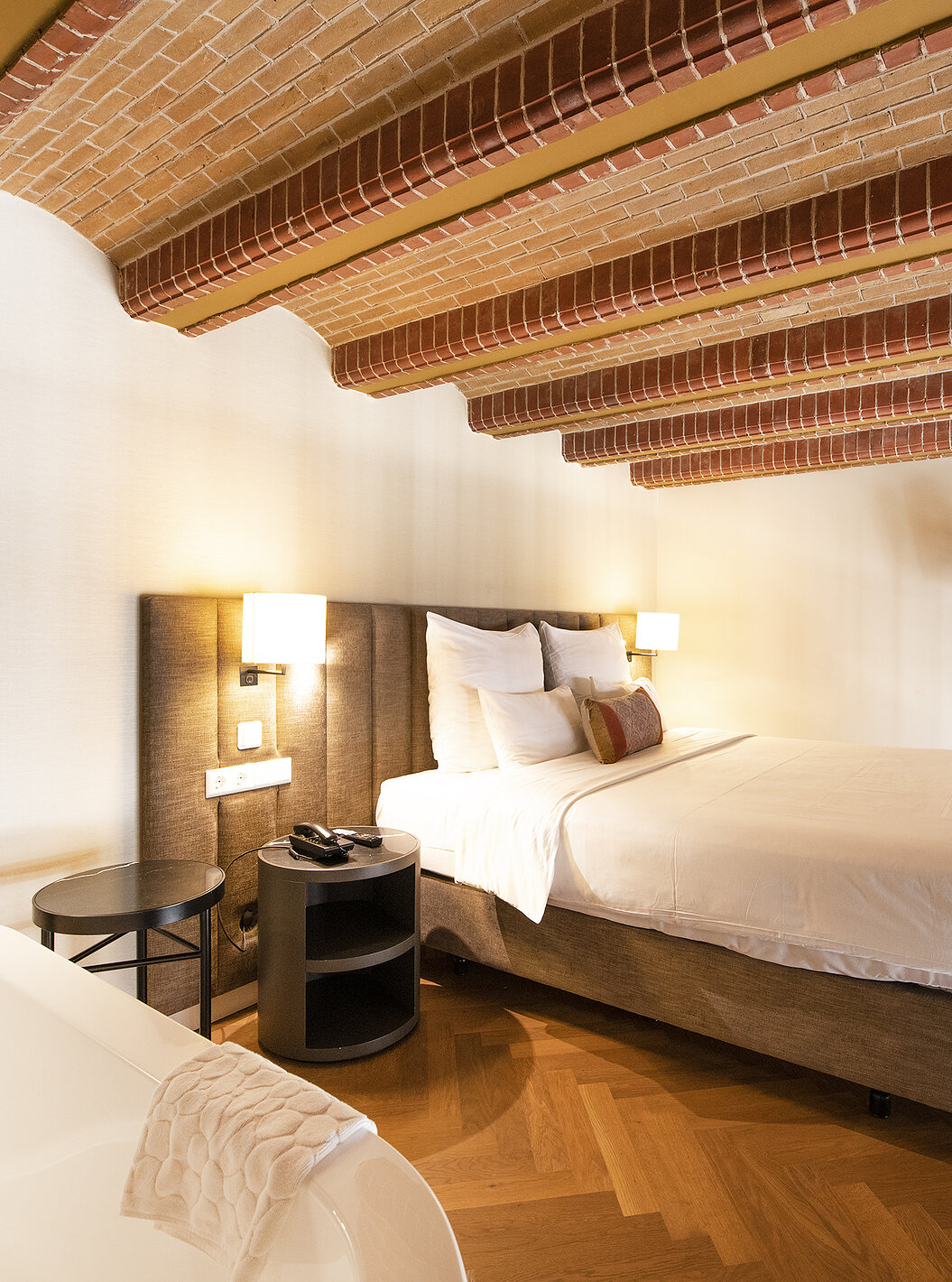 Mezzanine Suite at Pestana Amsterdam Riverside has a double bed, with bedside table, and red brick ceiling