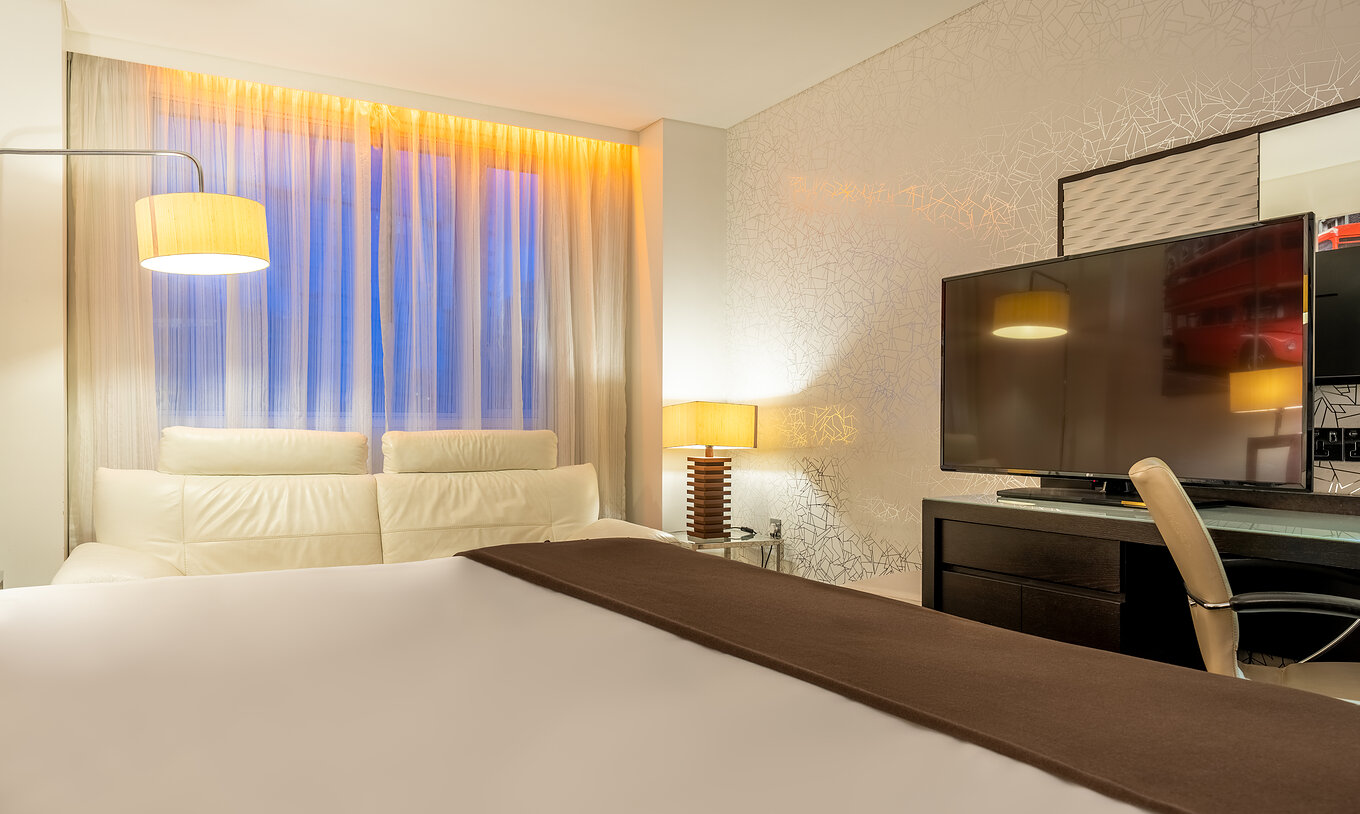 The Standard Disability at Pestana Chelsea Bridge has bed, desk with TV and chair, sofa and windows facing the city