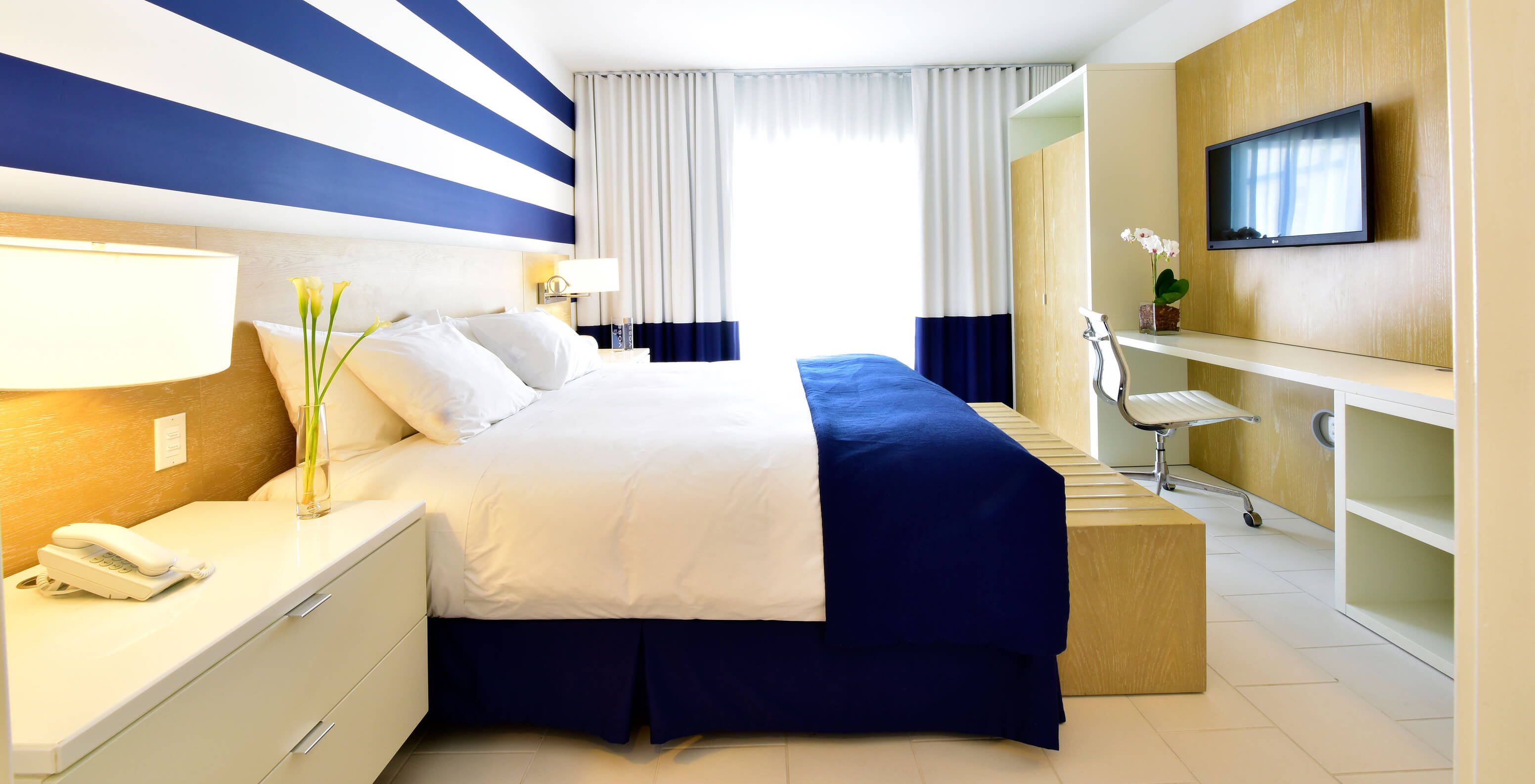 The Two Bedroom Suite with Balcony at Pestana Miami South Beach has a double bed, closet, TV and table