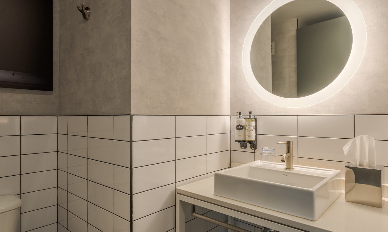 The Superior Double at Pestana CR7 Times Square has a bathroom with sink and a round mirror with lights around