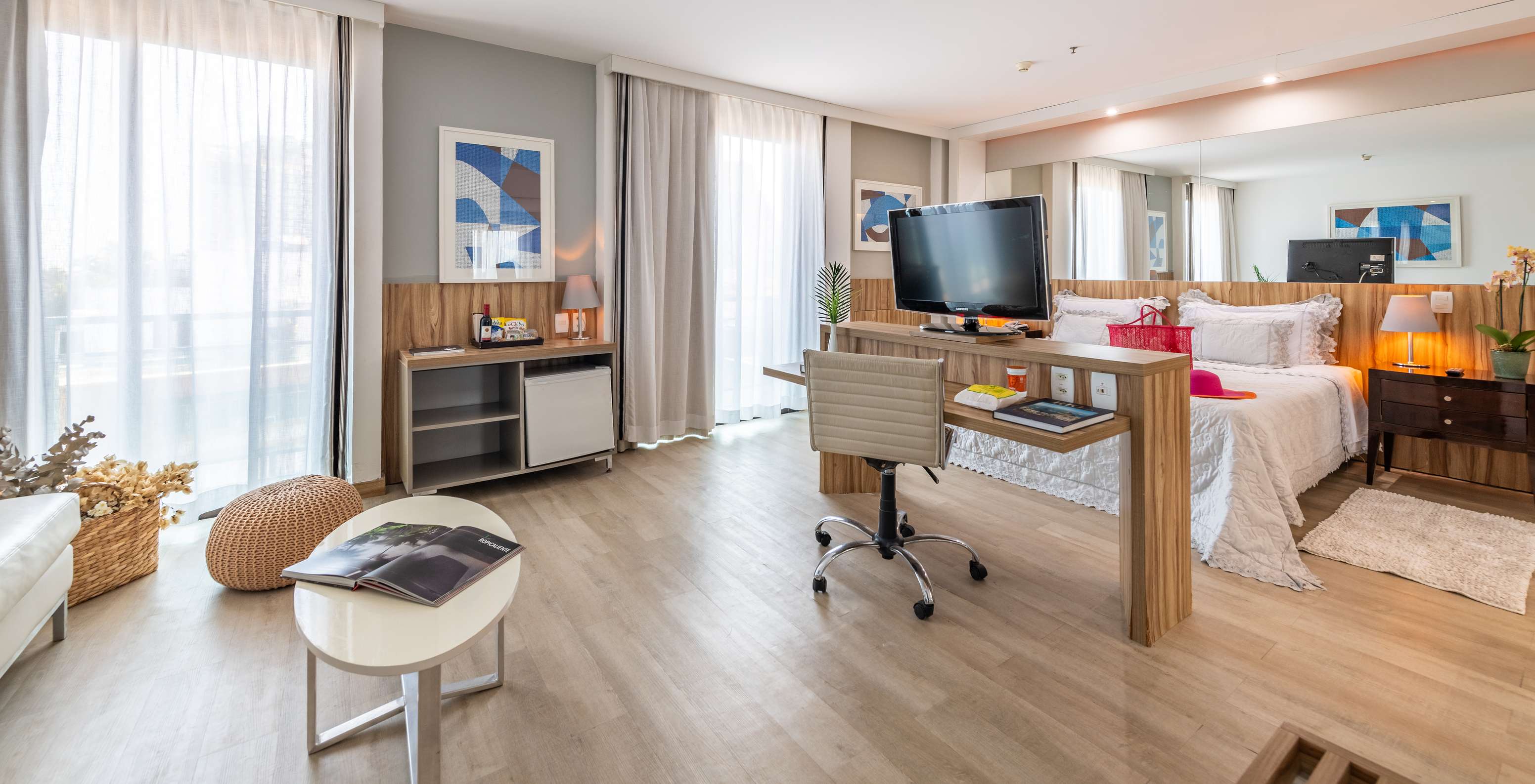 La Suite Junior con Vista Lateral al Mar del Pestana Rio Atlântica tiene una cama de casal, escritorio, televisión y dos ventanas con cortinas