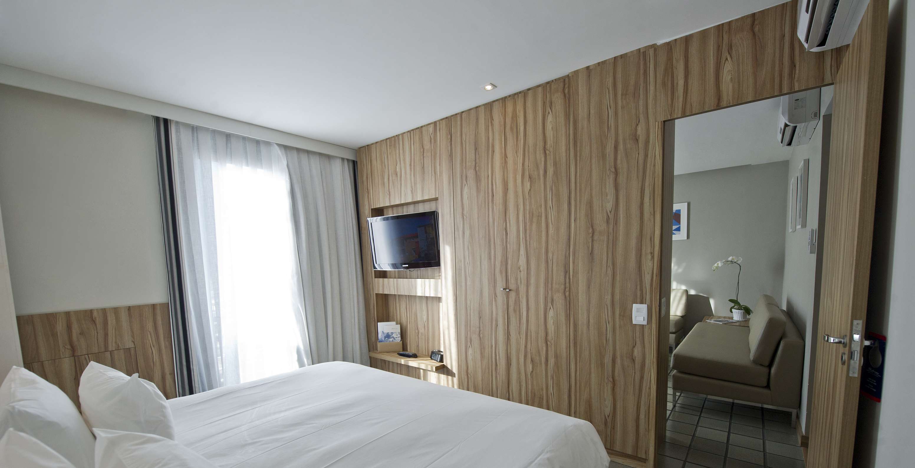 La Suite Estándar del Pestana Rio Atlântica tiene un cuarto con cama de casal y televisión, y una sala con sofás y aire acondicionado