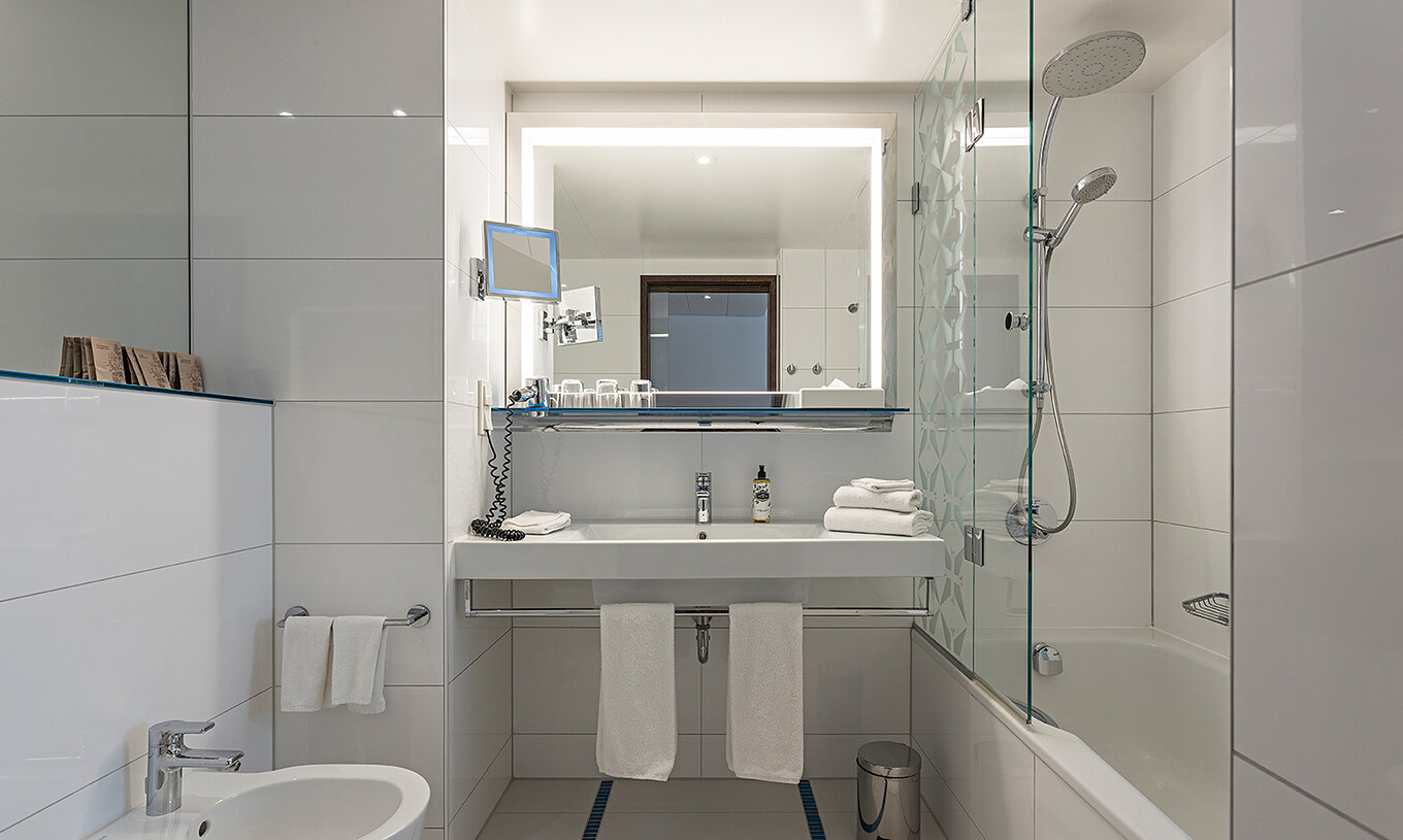 El Cuarto Deluxe del Pestana Berlin Tiergarten tiene baño con bañera y ducha, un lavabo y un espejo