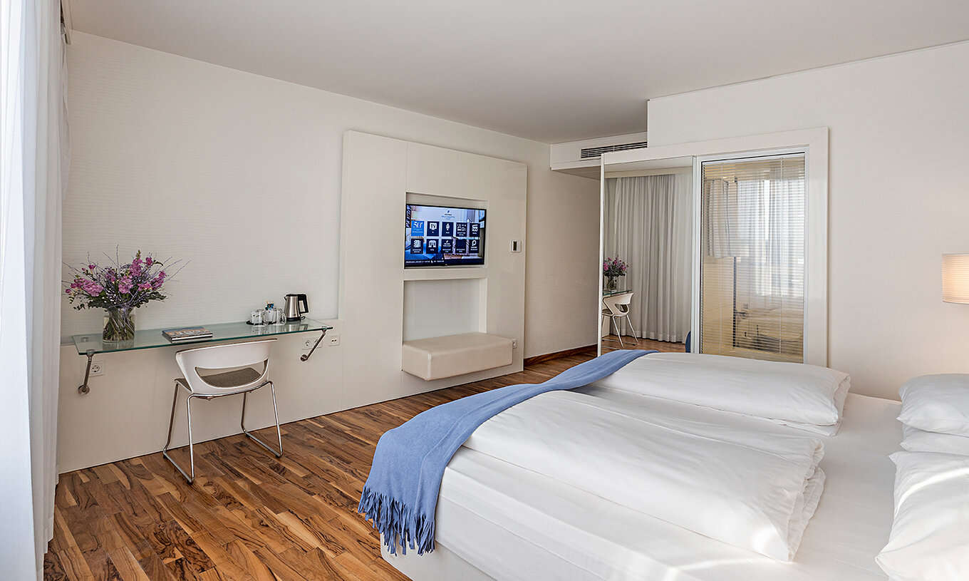 El Cuarto Deluxe del Pestana Berlin Tiergarten tiene televisión, escritorio con lámpara y silla, sofá y sillón