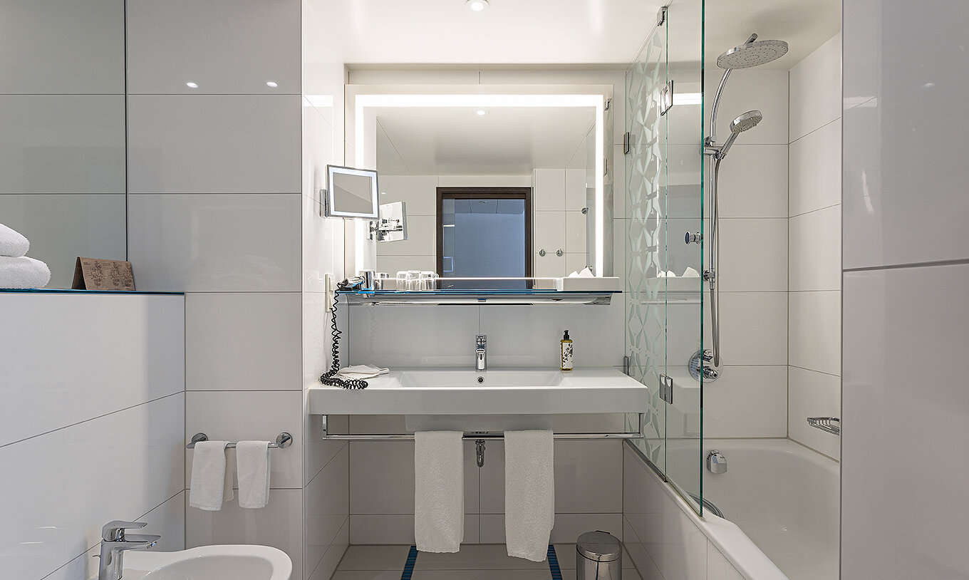 Family Deluxe con baño con bañera, ducha, lavabo y espejo.