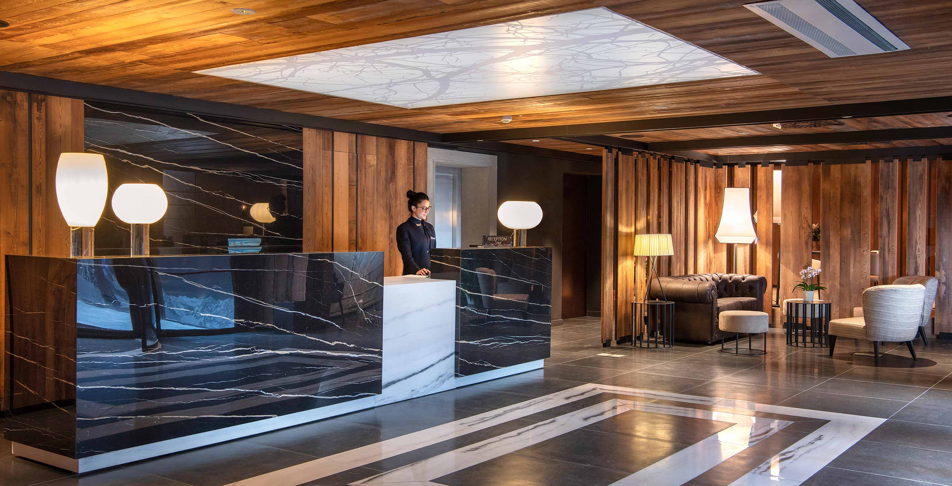 Le Massif Courmayeur, Hotel en los Alpes italianos, con recepción de mármol negro y salón iluminado