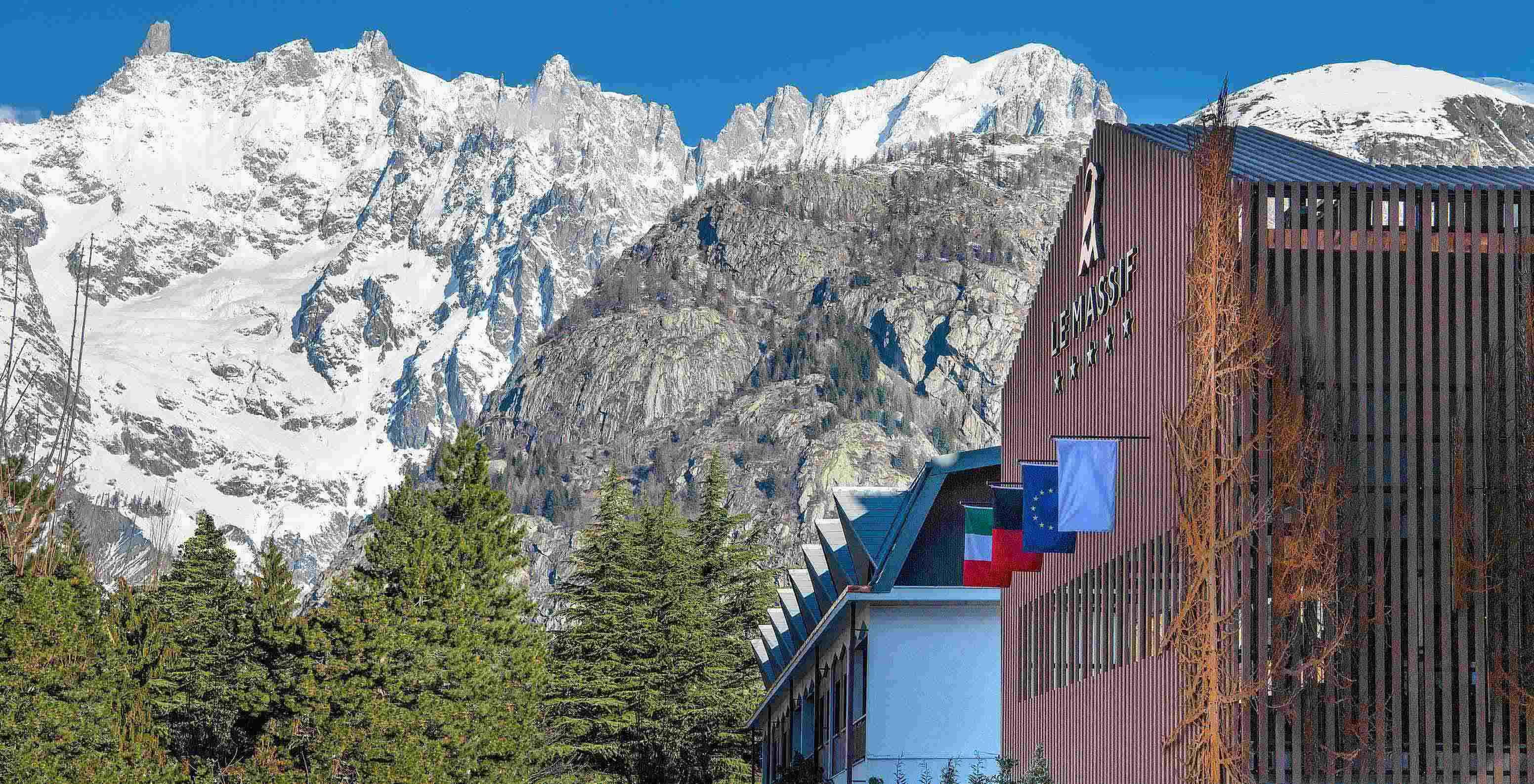 Fachada de Le Massif Courmayeur, Hotel en los Alpes italianos, frente a montañas nevadas y pinos altos
