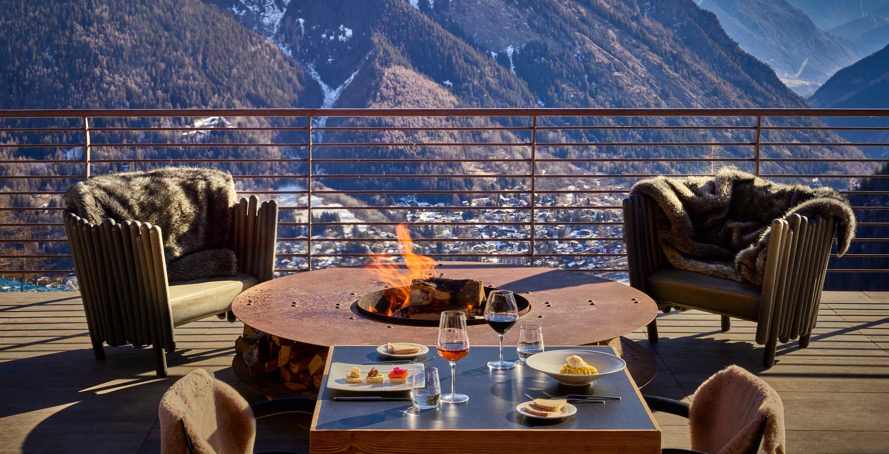 Le Massif Courmayeur, Hotel en los Alpes italianos, con terraza y fogón frente a montañas nevadas al atardecer