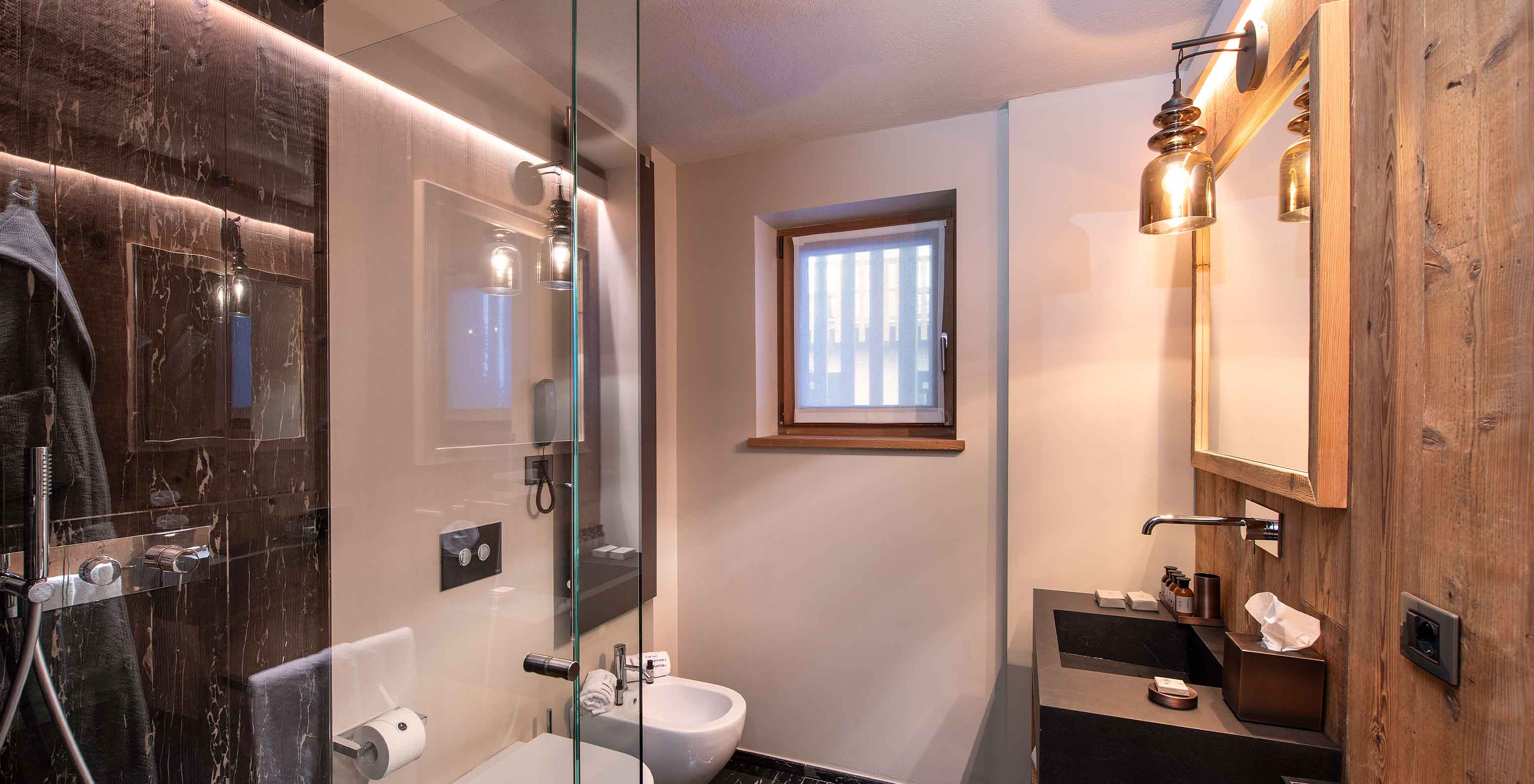 Le Massif Courmayeur Hotel en los Alpes italianos, con baño moderno de madera, ducha de vidrio y lavabo negro