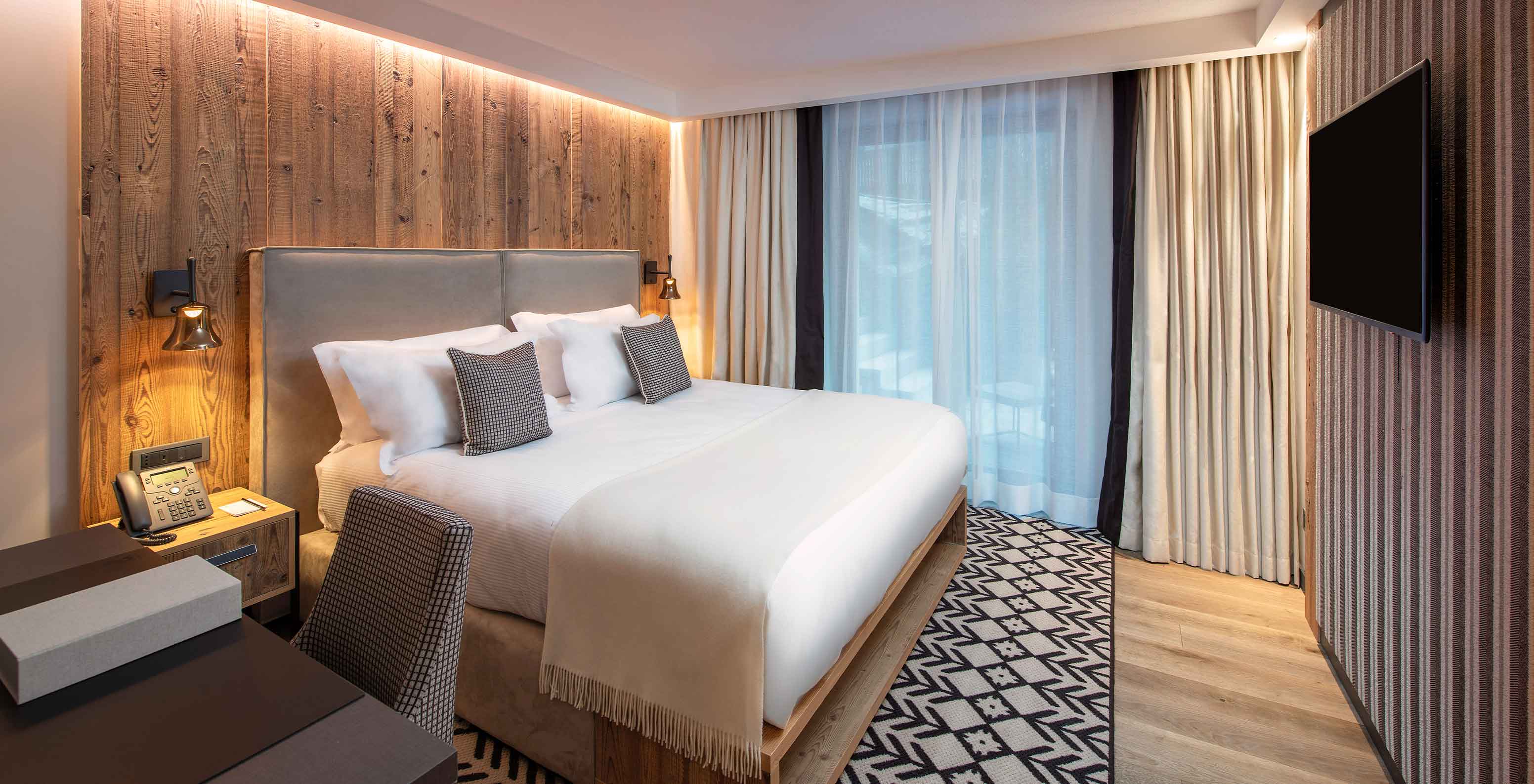 Le Massif Courmayeur, Hotel en los Alpes italianos, con dormitorio moderno de madera y cama doble frente al televisor