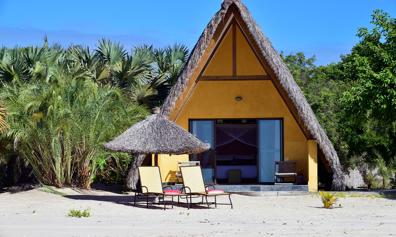 El Bungalow T1 del Pestana Bazaruto Lodge es una casita amarilla en la playa con techo de paja en forma de A