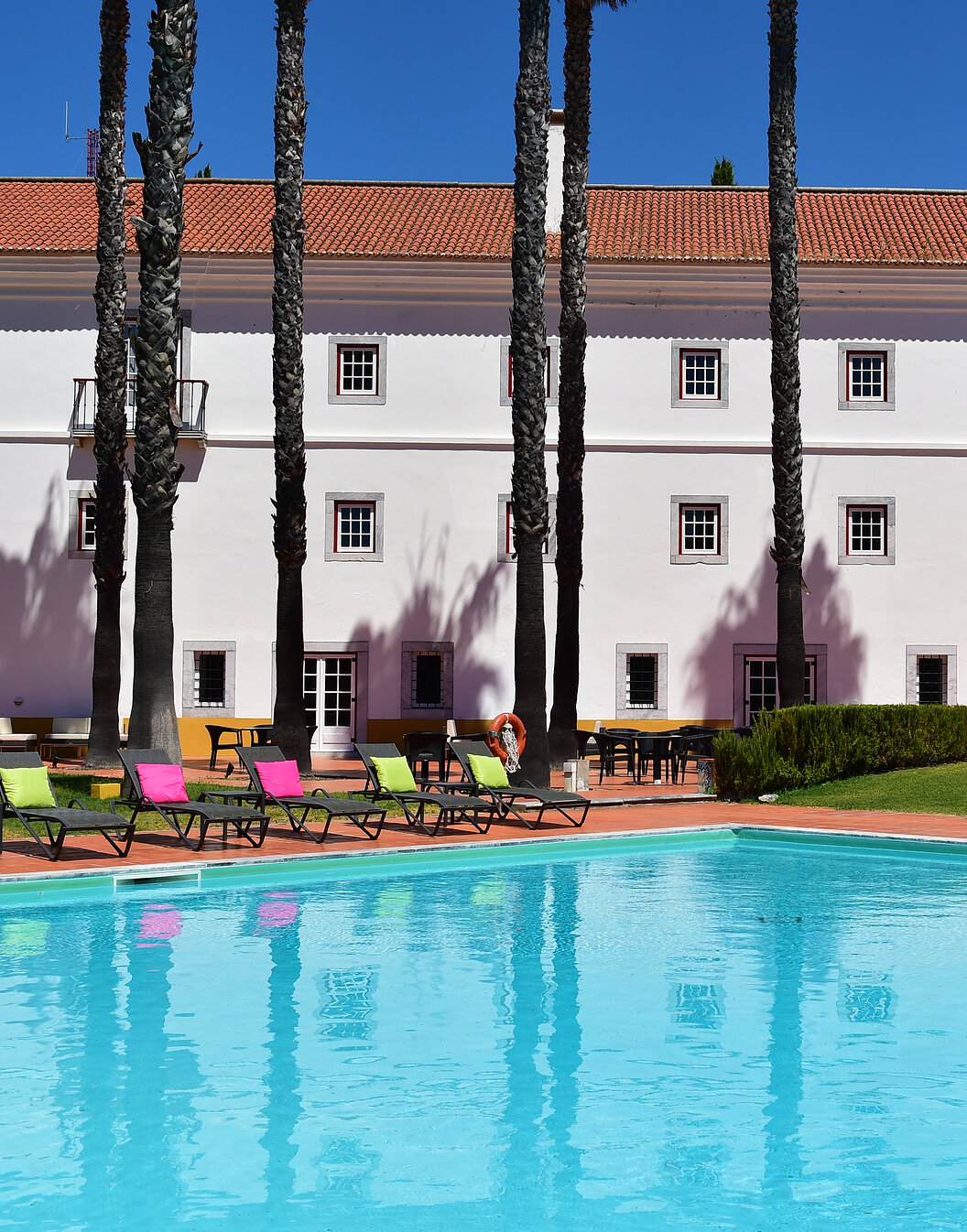 Piscina exterior de Pousada Convento Beja, un hotel histórico en Alentejo, con varias tumbonas con almohadas