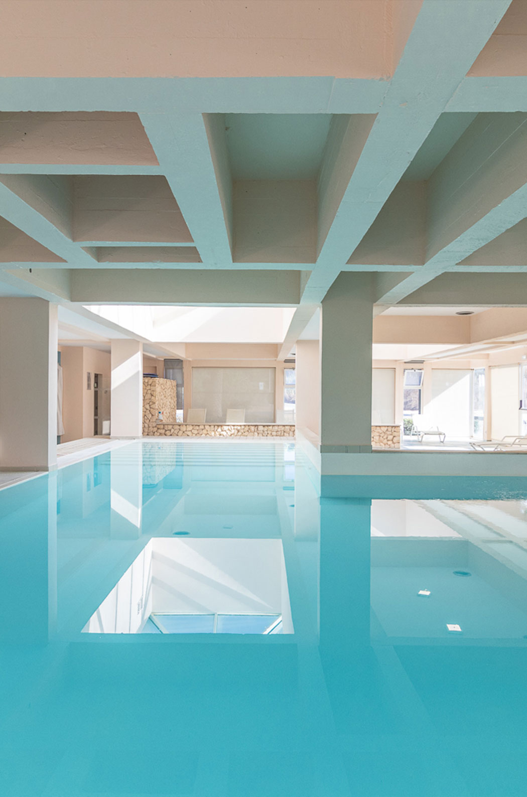 Piscina interior con luz natural y tumbonas en el aparthotel frente al mar