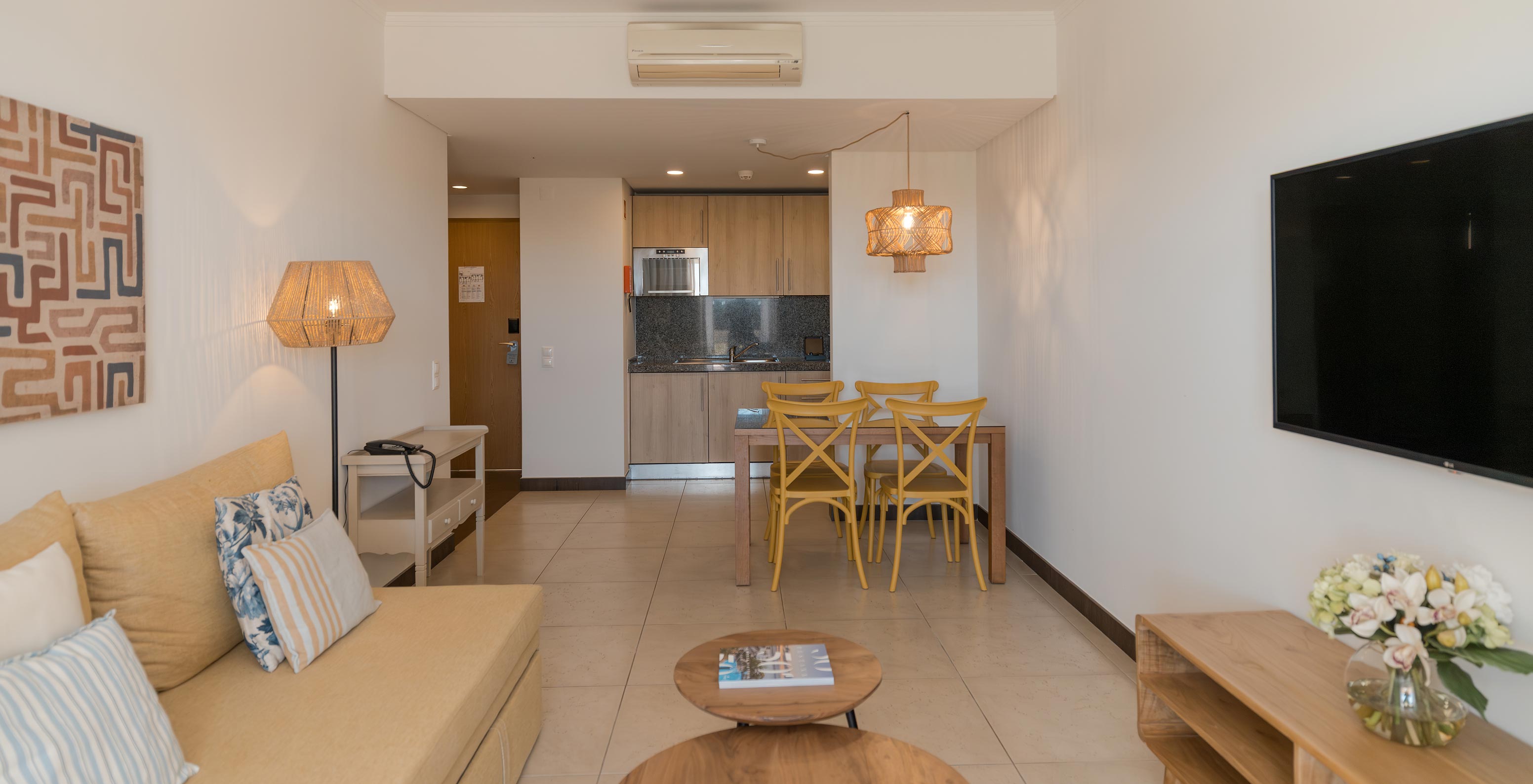 Apartamento T1 Vista Jardín en Pestana Alvor Beach Villas tiene una sala de estar con sofá, TV y mesa de comedor