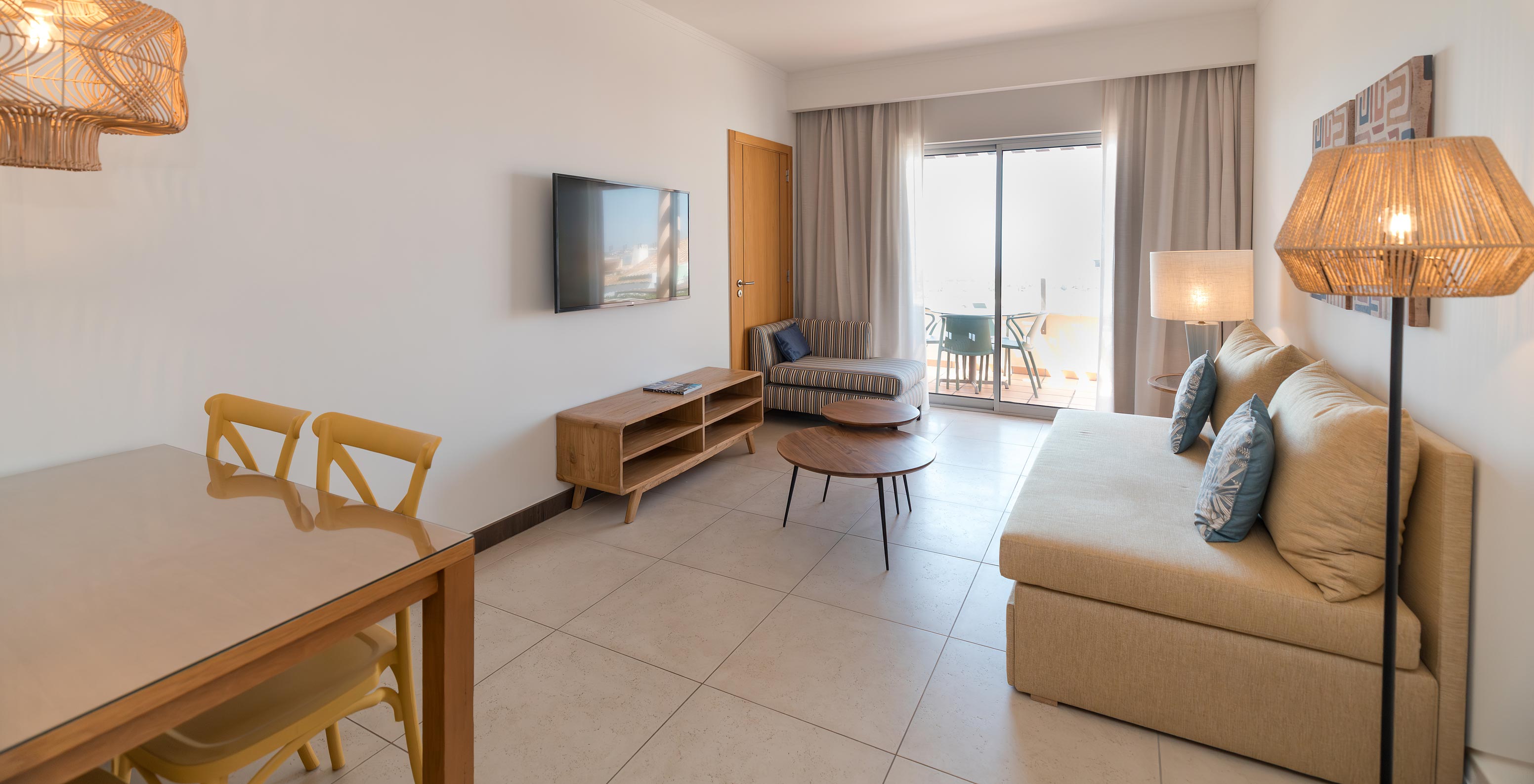 Apartamento T1 con vista al mar en Pestana Alvor Beach Villas tiene sala de estar con sofá, TV y ventana con acceso al balcón
